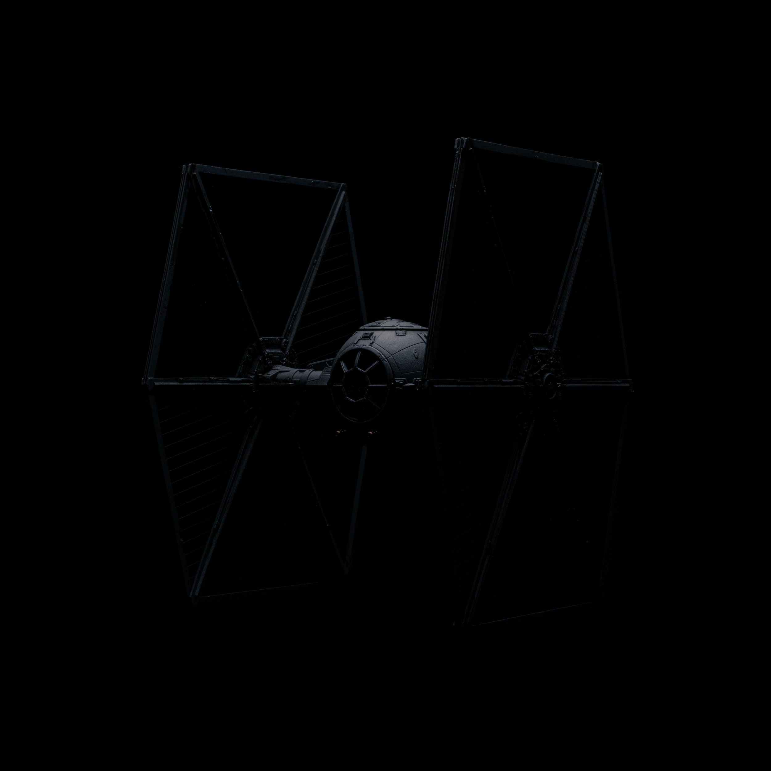 Ein auf dem All schwarzen Hintergrund befindlicher TIE Fighter aus dem Star-Wars-Universum, mit reflektierender Oberfläche und offenen Flügeln.