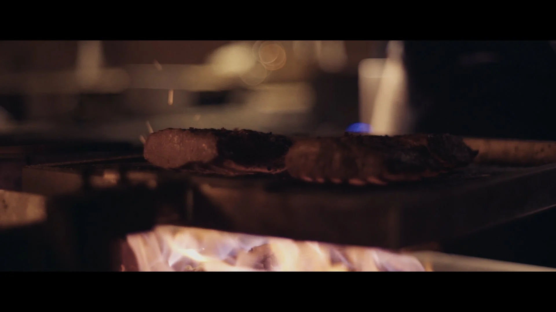 Ein Stück Steak brät auf einem Grill über offenen Flammen.