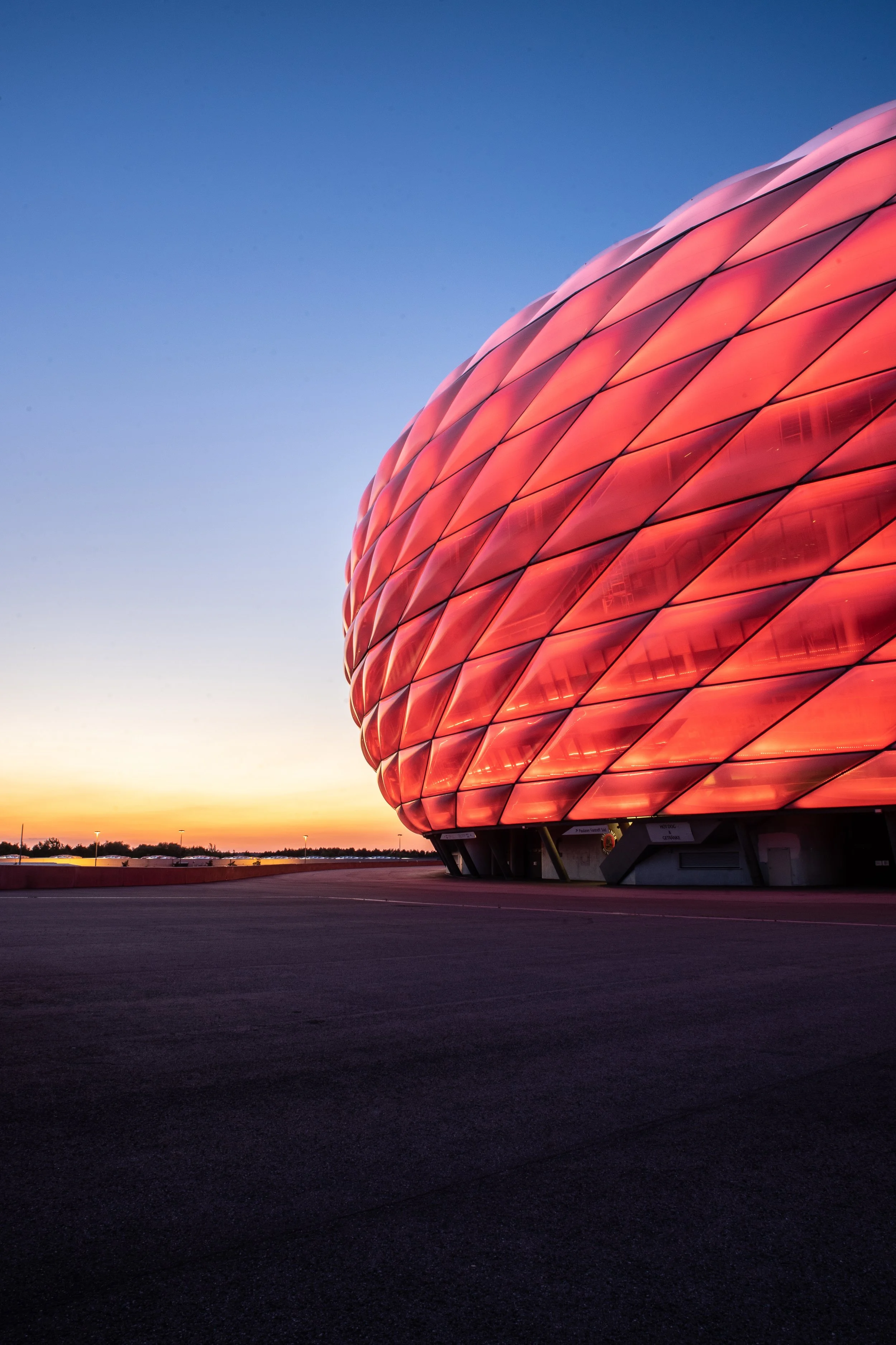 Modernes, einzigartiges Gebäude mit leuchtend rotem, schuppenartigem Fassadendesign bei Sonnenuntergang.