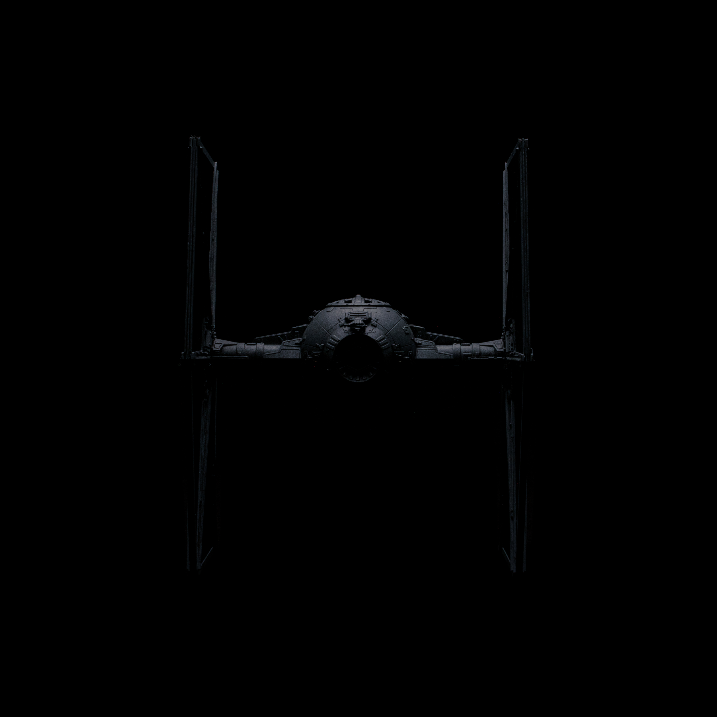 Ein Star Wars TIE Fighter im All, kaum sichtbar gegen den schwarzen Hintergrund.