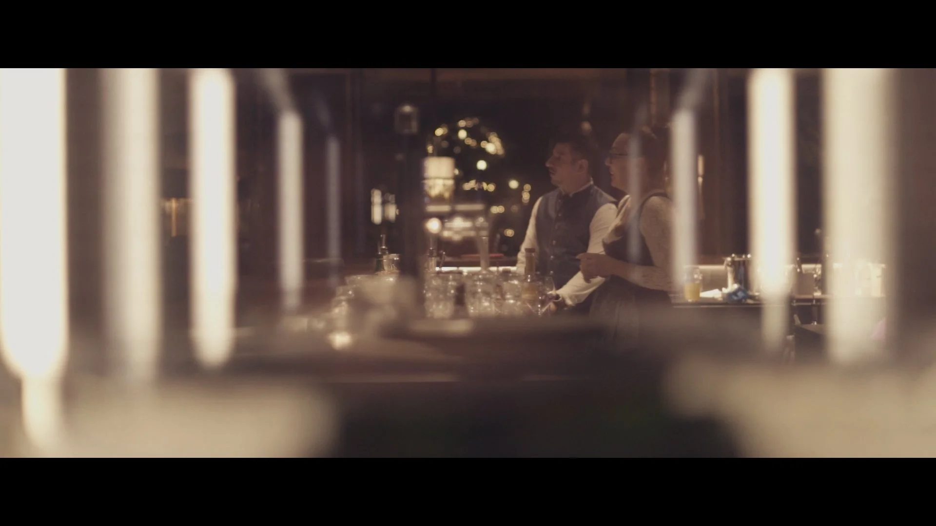 Zwei Servicekräfte in einem Restaurant bei der Arbeit, Blick durch eine Gardine oder einen dekorativen Raumteiler