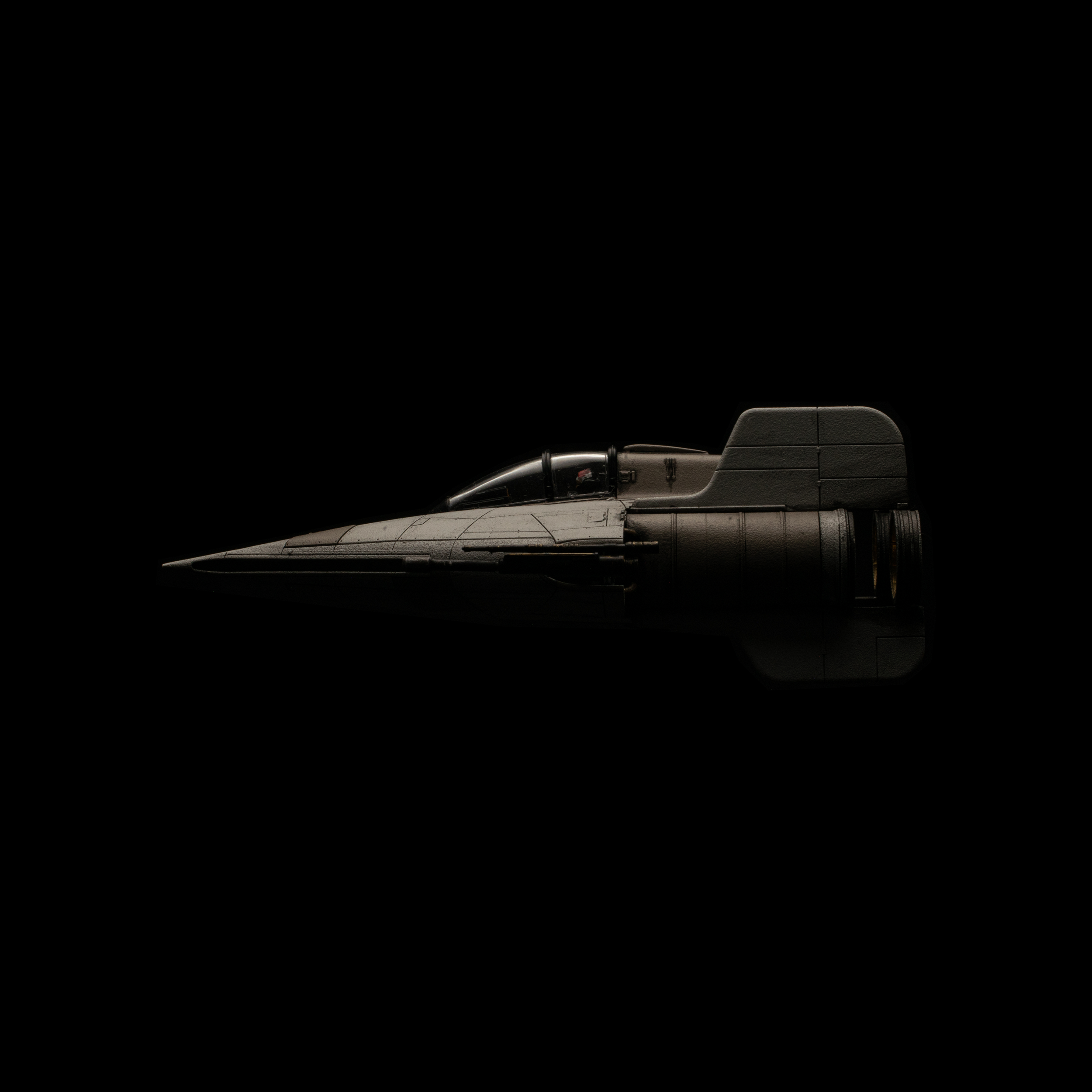 Dieses Bild zeigt ein schwarzes Modellflugzeug mit langer, spitzer Nase und einem geschlossenen Cockpit, das vor einem schwarzen Hintergrund abgebildet ist.