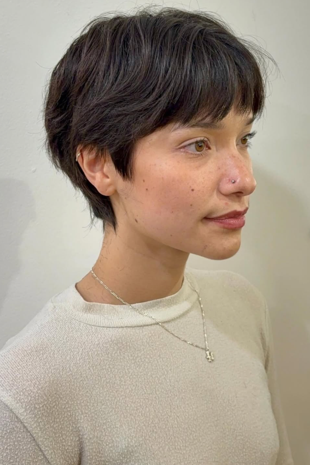 Girl wearing a Soft Pixie with Texture haircut, featuring short layered strands styled for soft volume and movement.