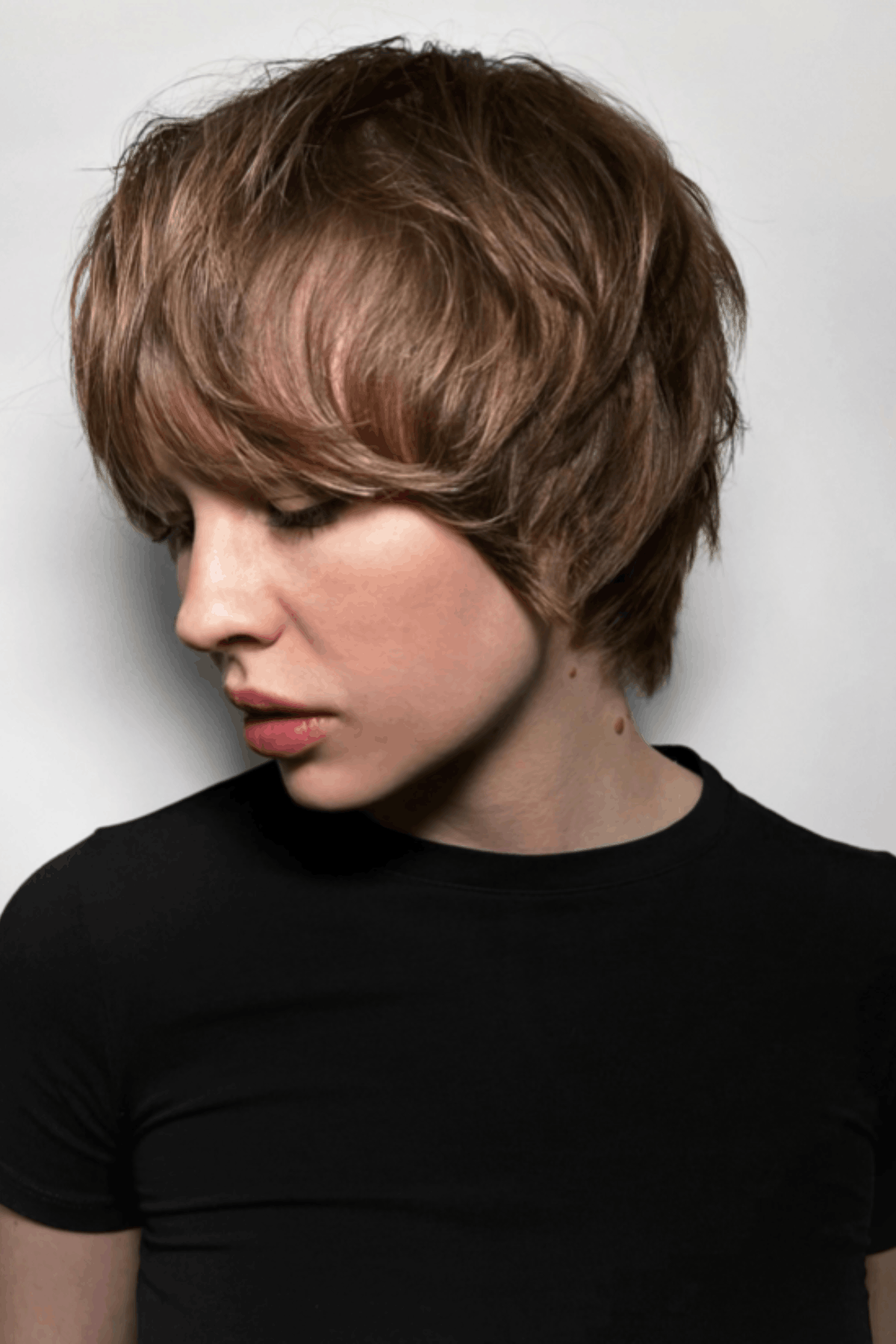 Side-profile image of a person wearing Long Pixie with Sweeping Side Fringe, featuring extended length through the top with a soft, sweeping side fringe that blends into layered sides and a tapered back.