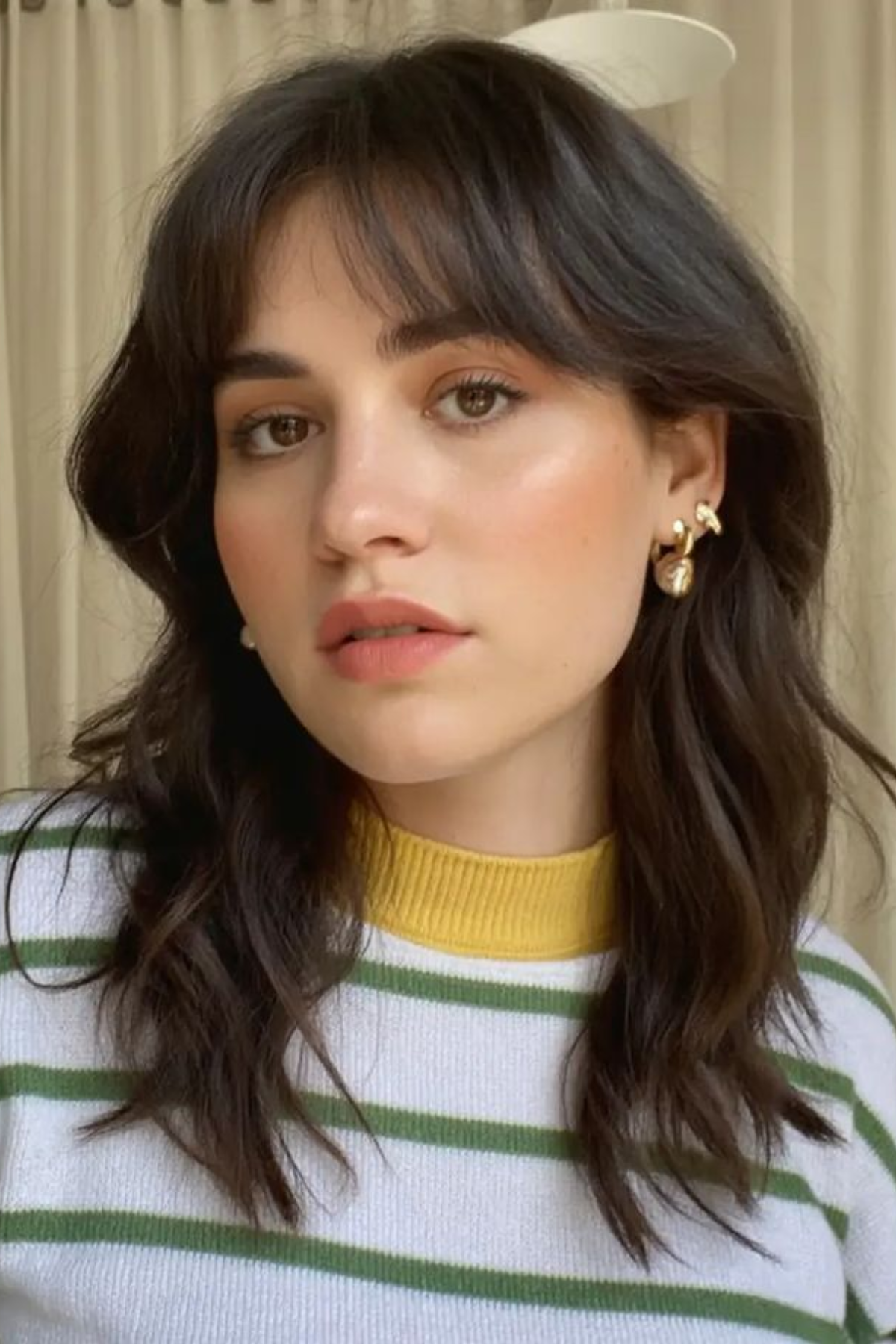 Woman wearing a Modern Shag with Curtain Bangs haircut, combining choppy layers with parted bangs framing the face.