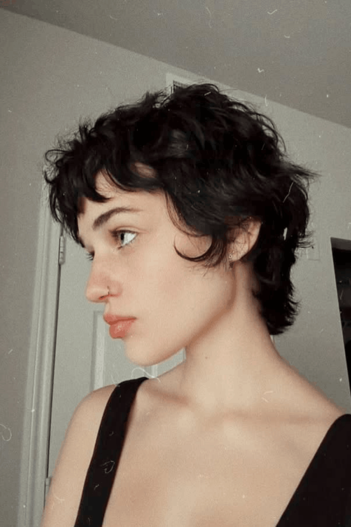 Side-profile image of a person wearing The Textured Pixie with Crown Volume, displaying a short pixie cut with pronounced texture and lifted volume concentrated at the crown.