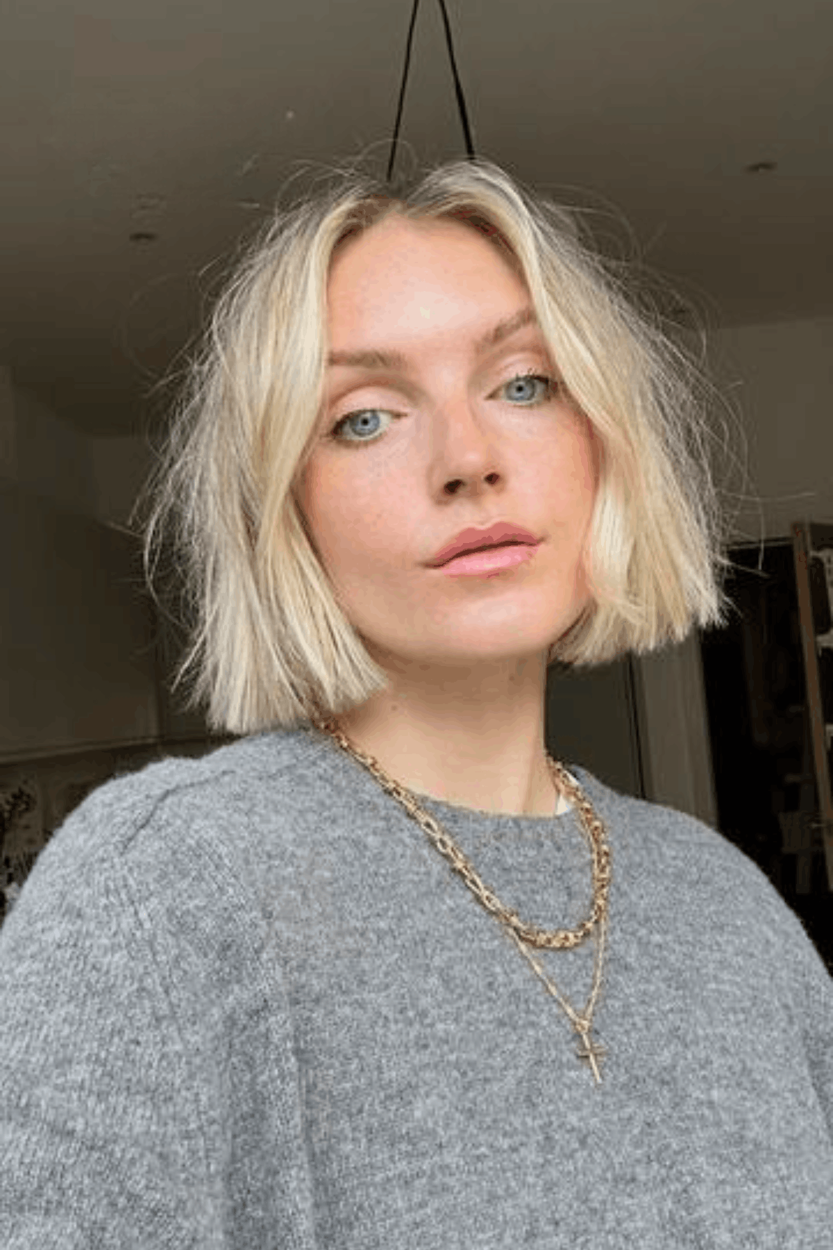 Portrait of a woman with a blonde textured layered bob with wispy ends, styled with soft movement and airy texture.