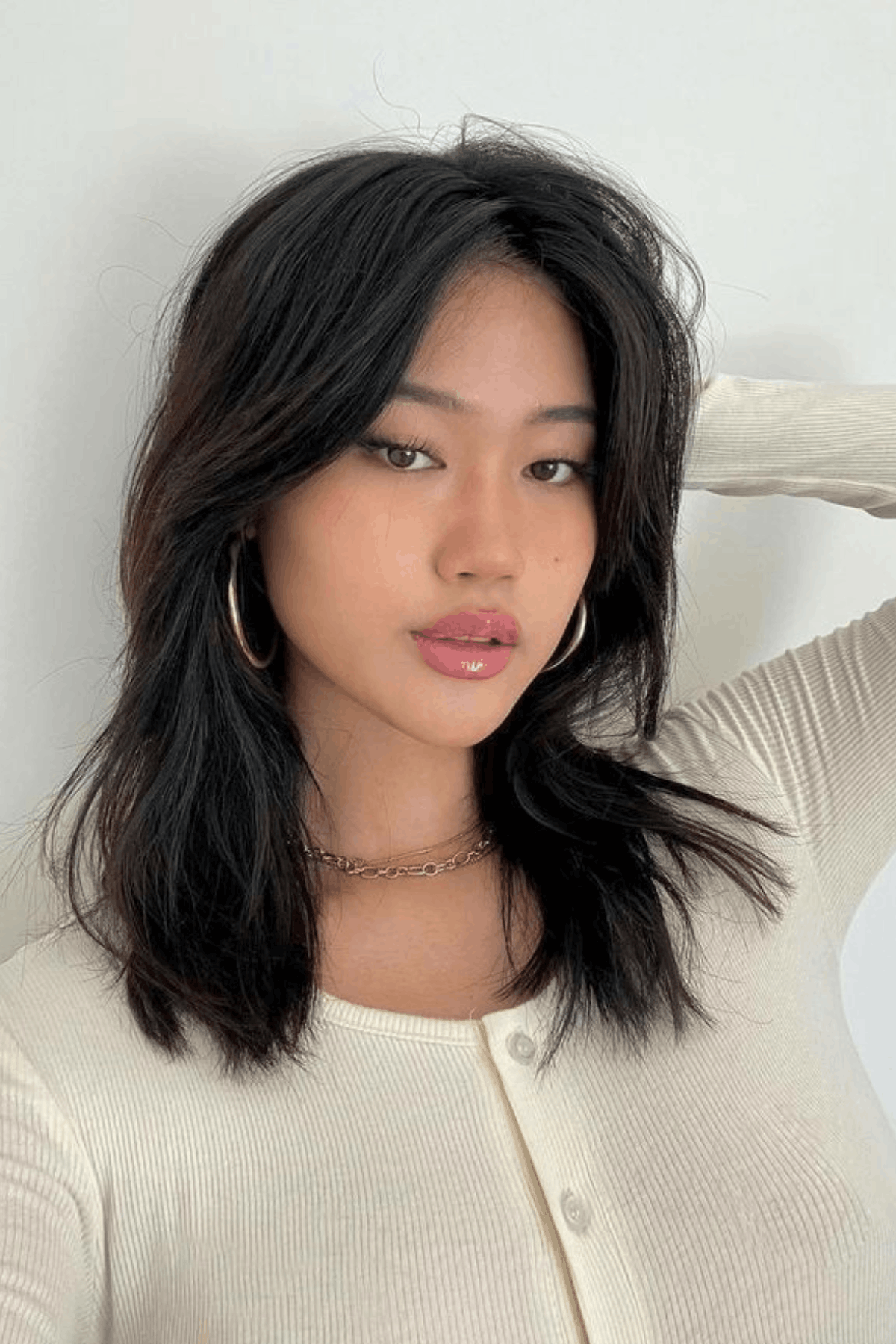 Woman with a textured butterfly cut, blending layered butterfly structure with a soft wolf-cut influence, creating piecey ends and natural, tousled volume.