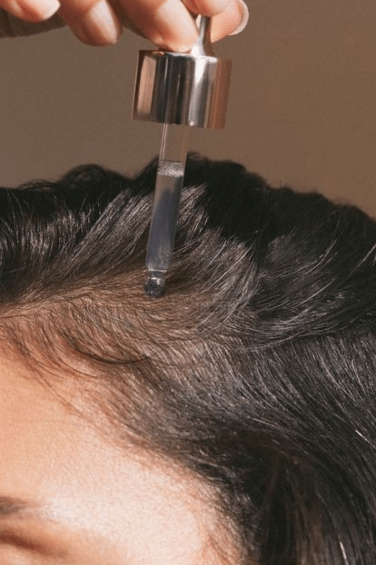 An image of a women oiling her scalp