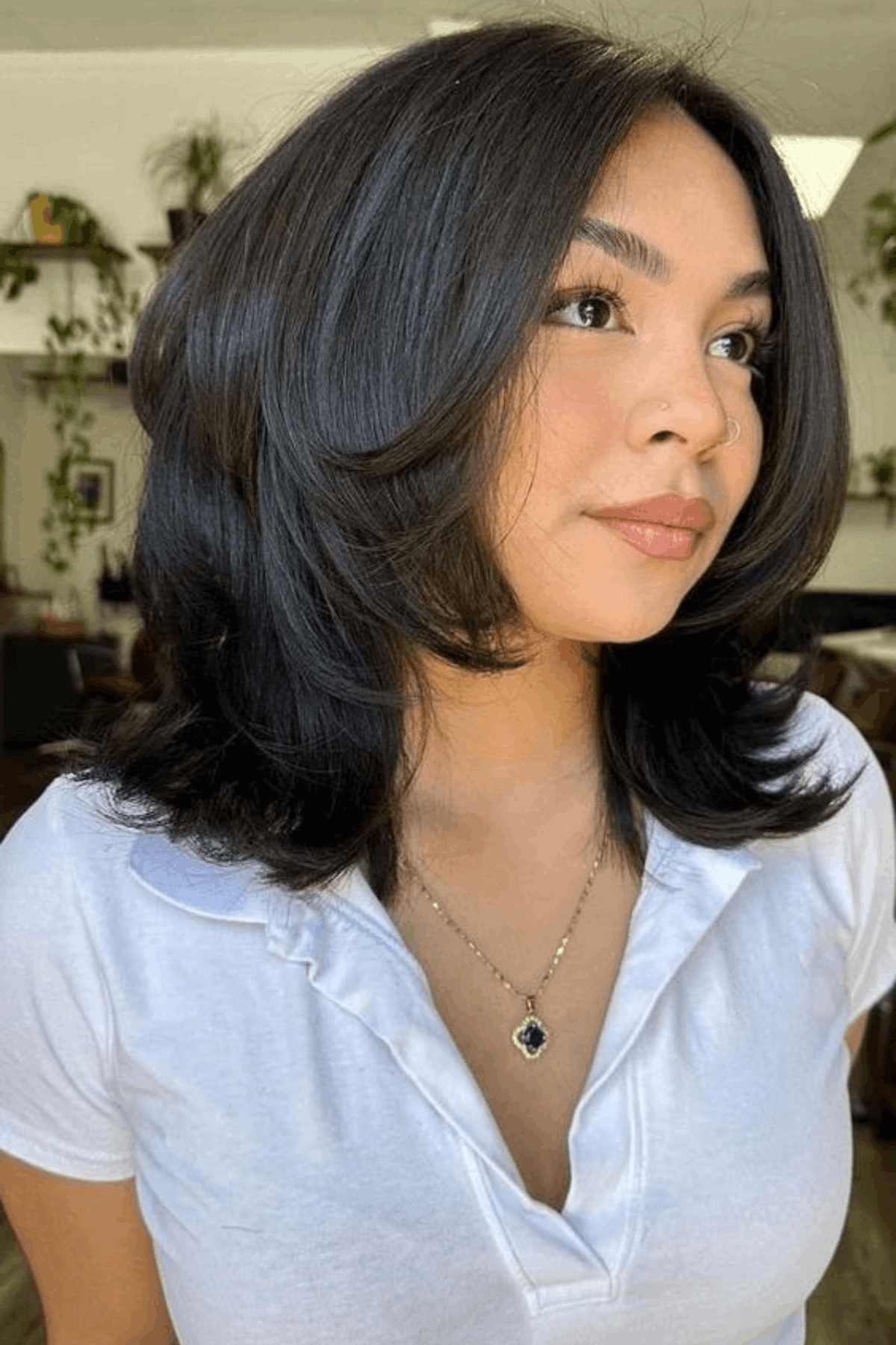 Woman with a medium-short butterfly haircut, featuring layered volume through the mid-lengths and ends with soft outward movement around the shoulders.