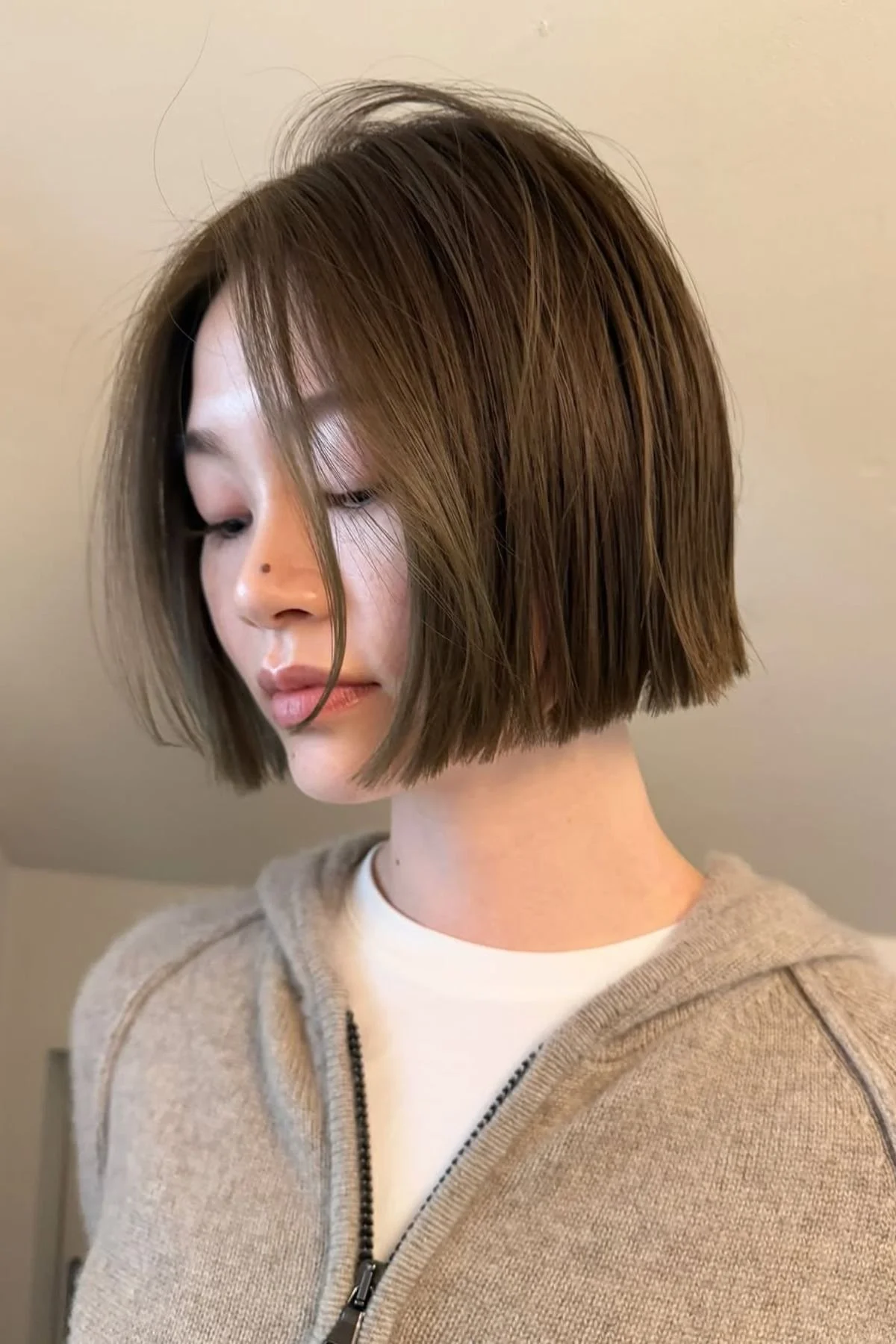 Girl styled in a Jaw-Hugging Blunt Bob with Curtain Bangs, combining a sharp bob cut with softly parted, face-framing fringe.