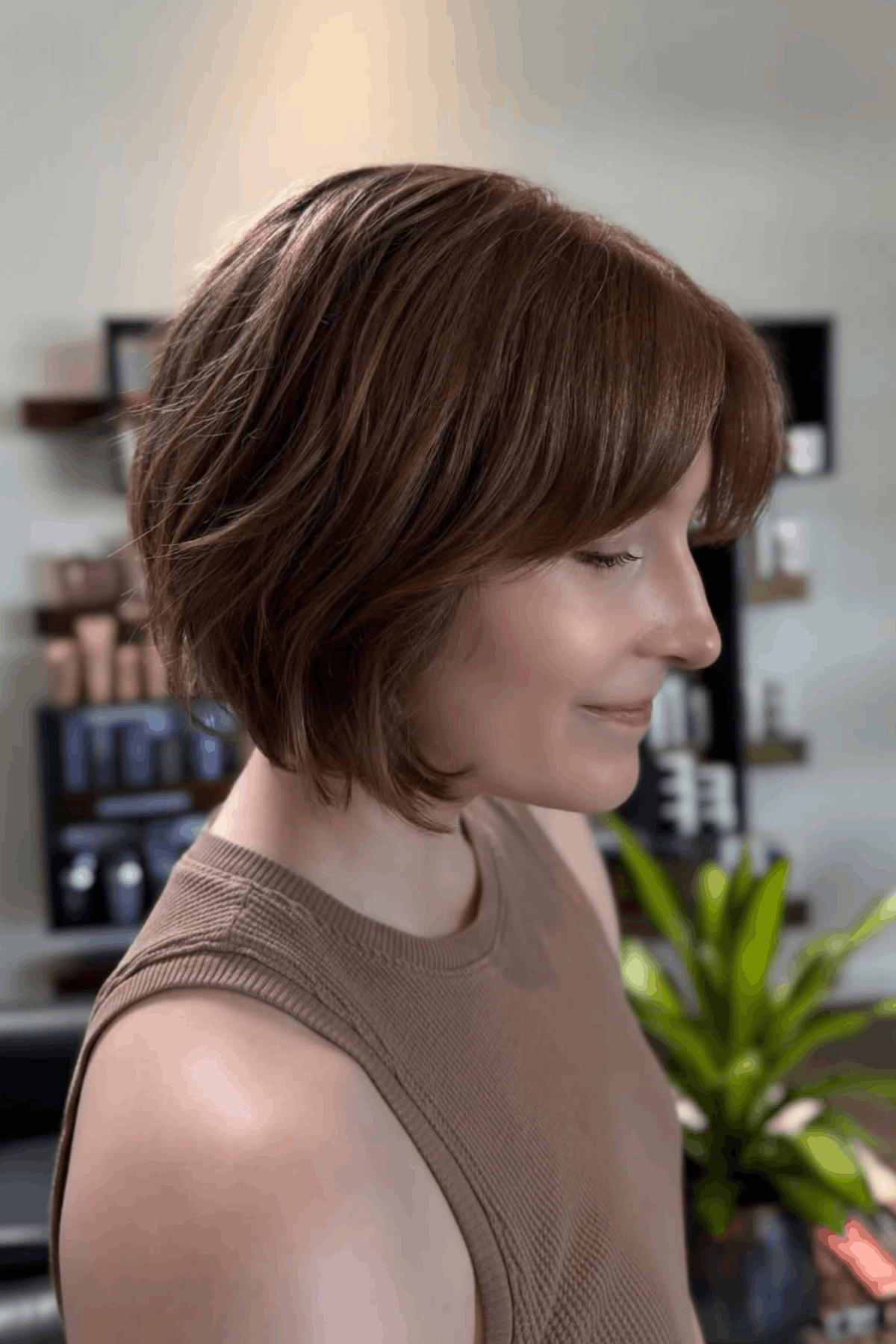 Side profile of a woman with a soft brown short layered bob for fine hair, styled with light layers to create fullness and shape.