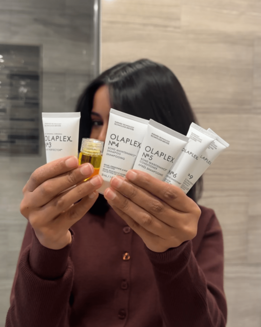 Jen holding up all the products that are in the Olaplex The Mini Essentials Set