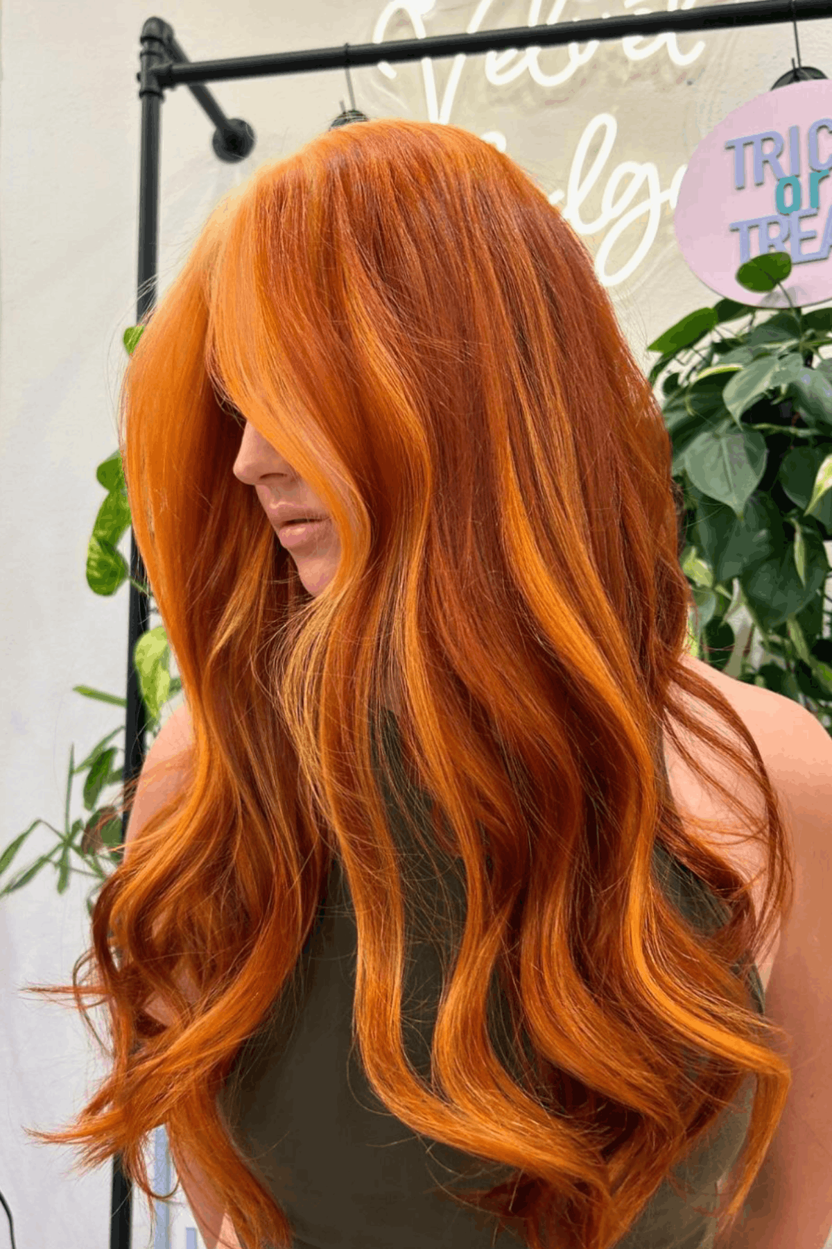 Woman with long, rich pumpkin orange hair, styled in loose waves with deep, warm autumn-inspired tones.