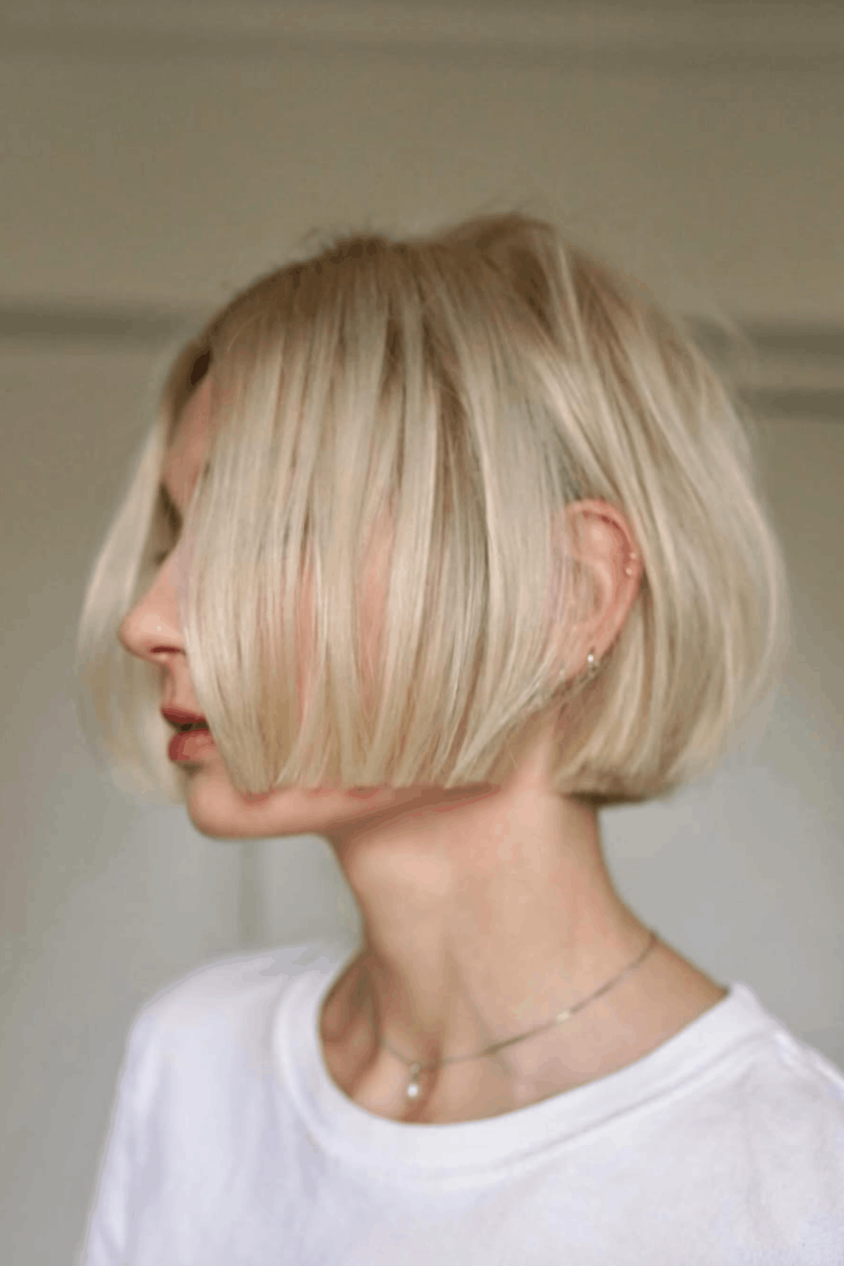 Woman with a very short blunt micro bob, cut sharply at chin level with clean, straight edges and a sleek finish.