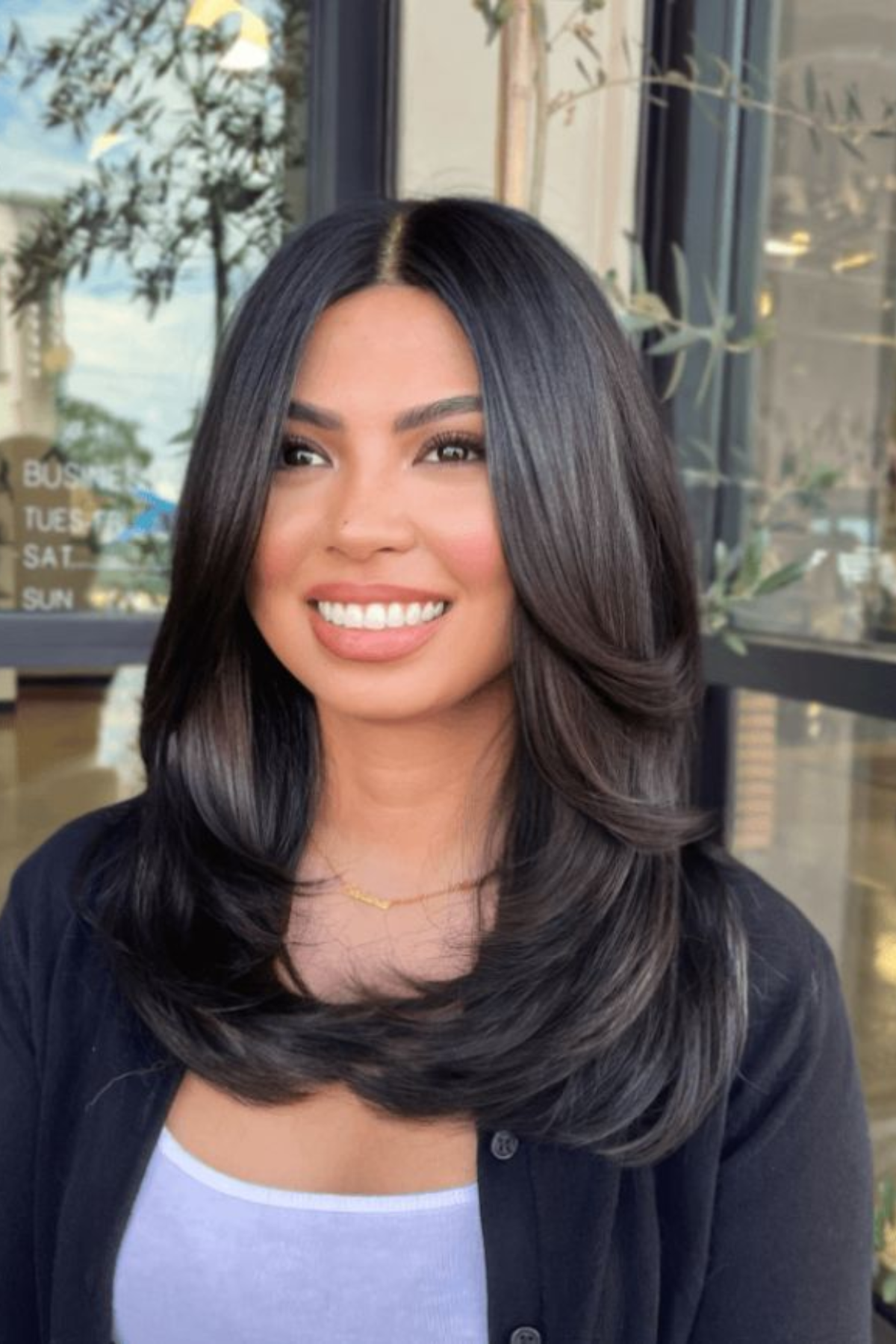 Girl styled in Butterfly Layers haircut with airy, cascading layers that remove weight while keeping length for summer.