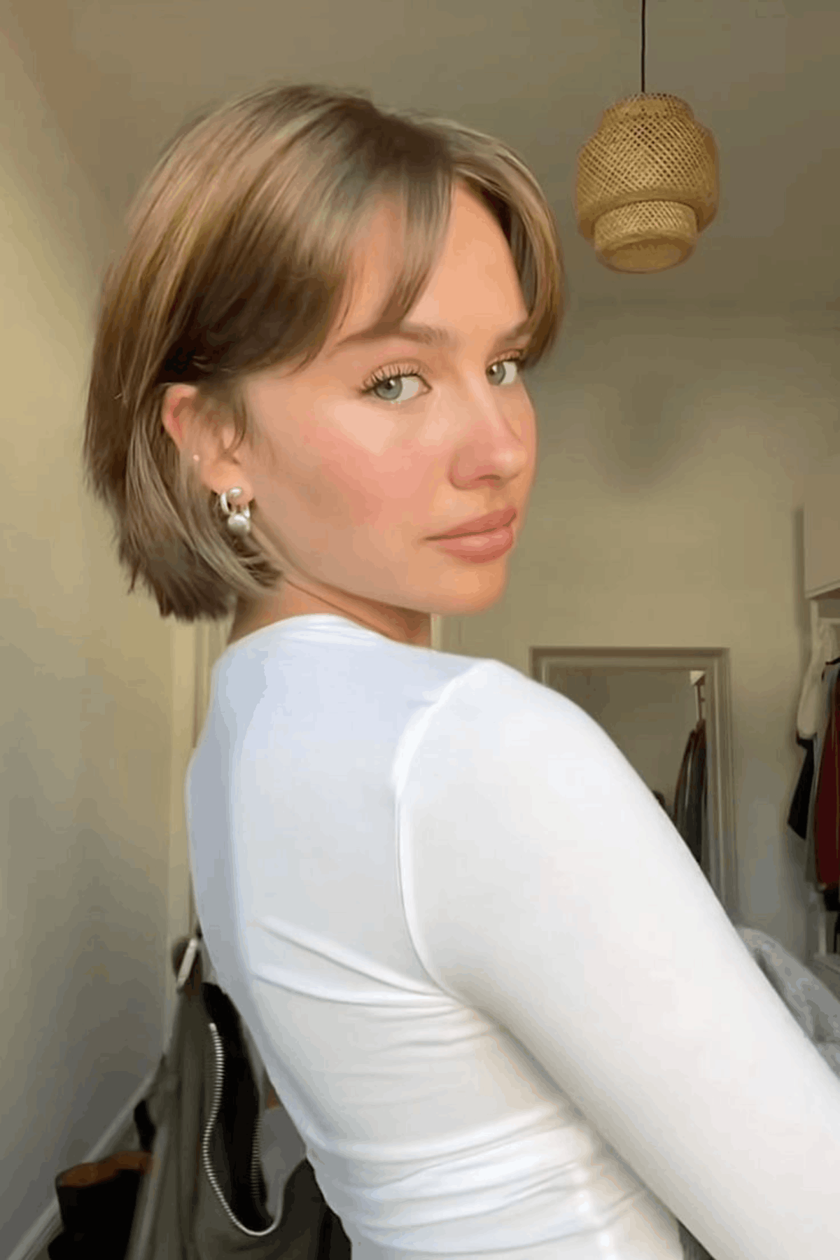 Woman with a short bixie haircut, blending pixie and bob elements with tapered layers, soft volume, and side-swept bangs.