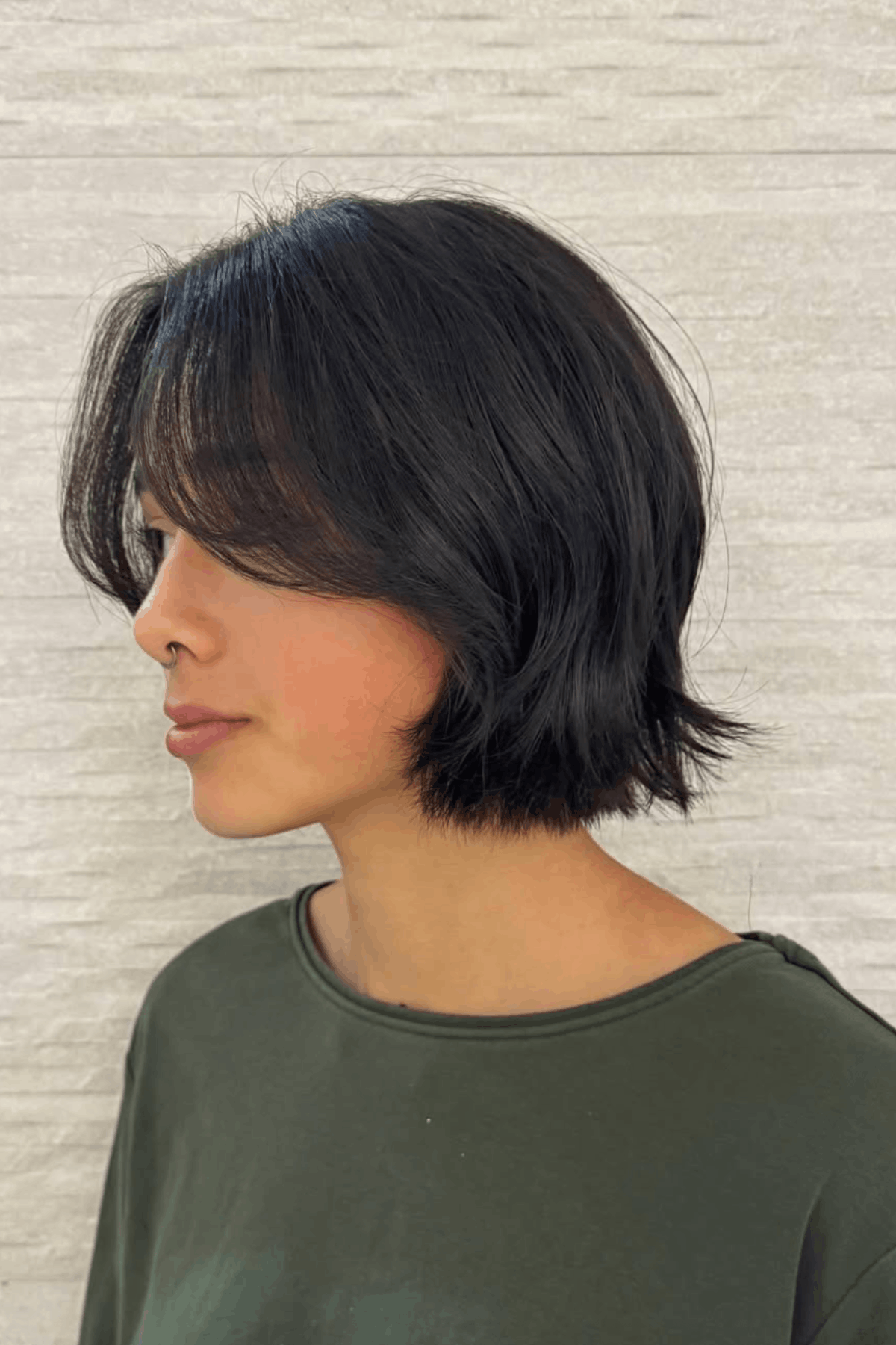 Woman with a soft layered bob, featuring subtle crown-focused layers for gentle lift and natural movement.