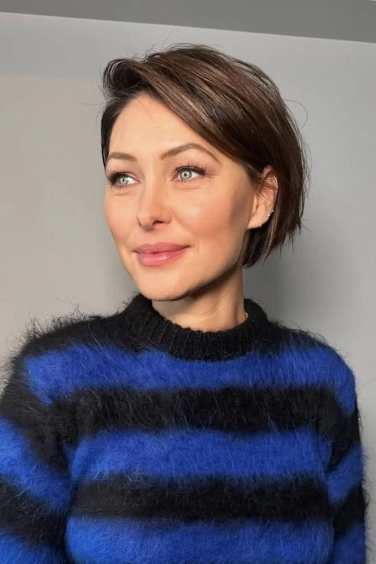 Woman wearing a Tapered Pixie with Volume haircut, featuring shorter tapered sides and lifted textured layers on top.