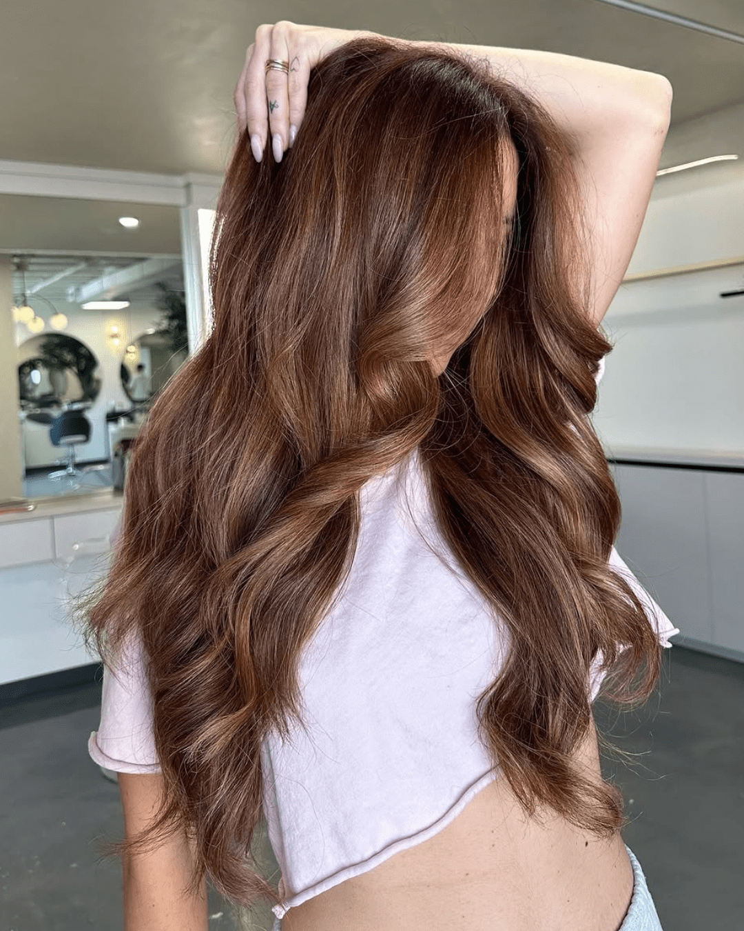 Cinnamon-Honey Balayage for Medium Skin Tones with long waves and warm blended tones.