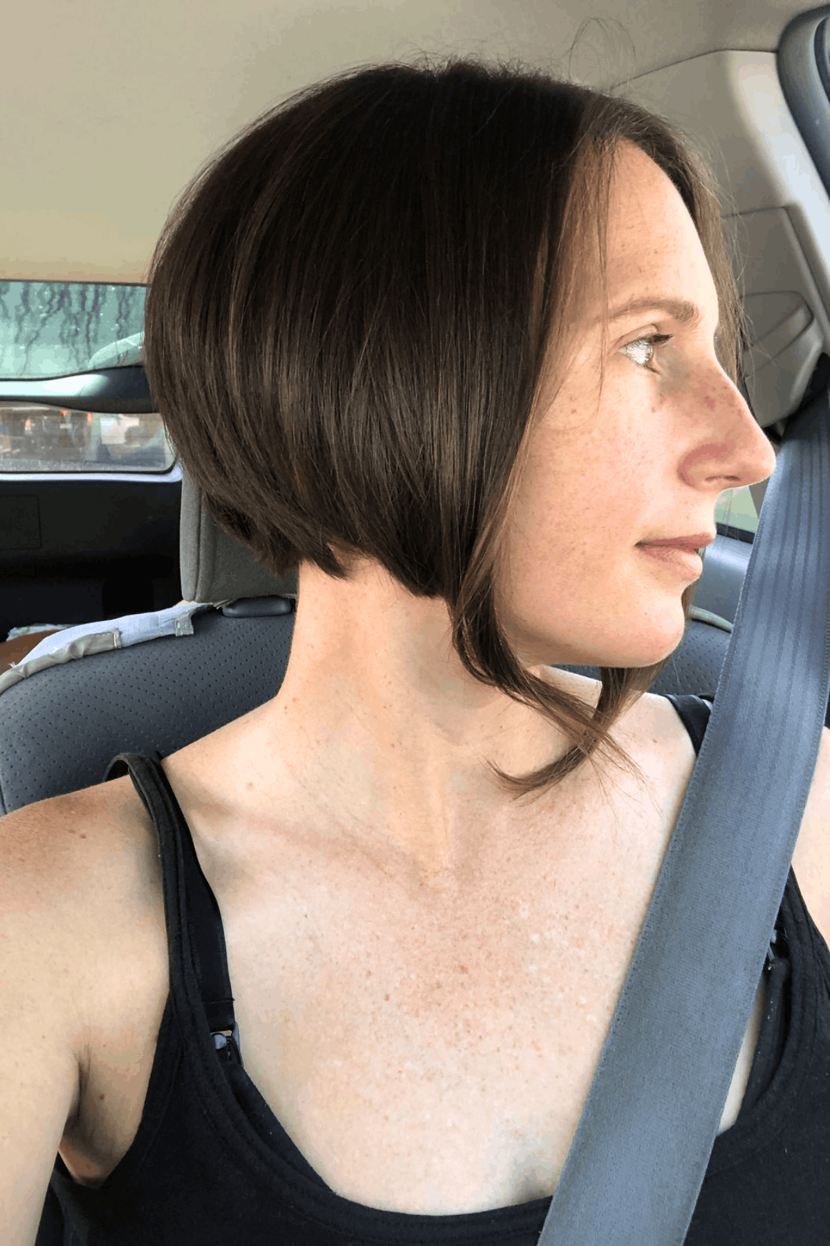 Salon scene showing a stylist standing behind a seated client, evaluating and preparing long hair before cutting, emphasizing consultation before going short.