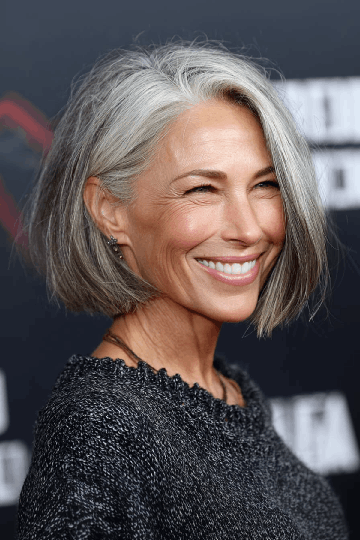 Portrait of a smiling woman with a silver short layered bob for women over 60, styled with soft layers and a side-swept front.