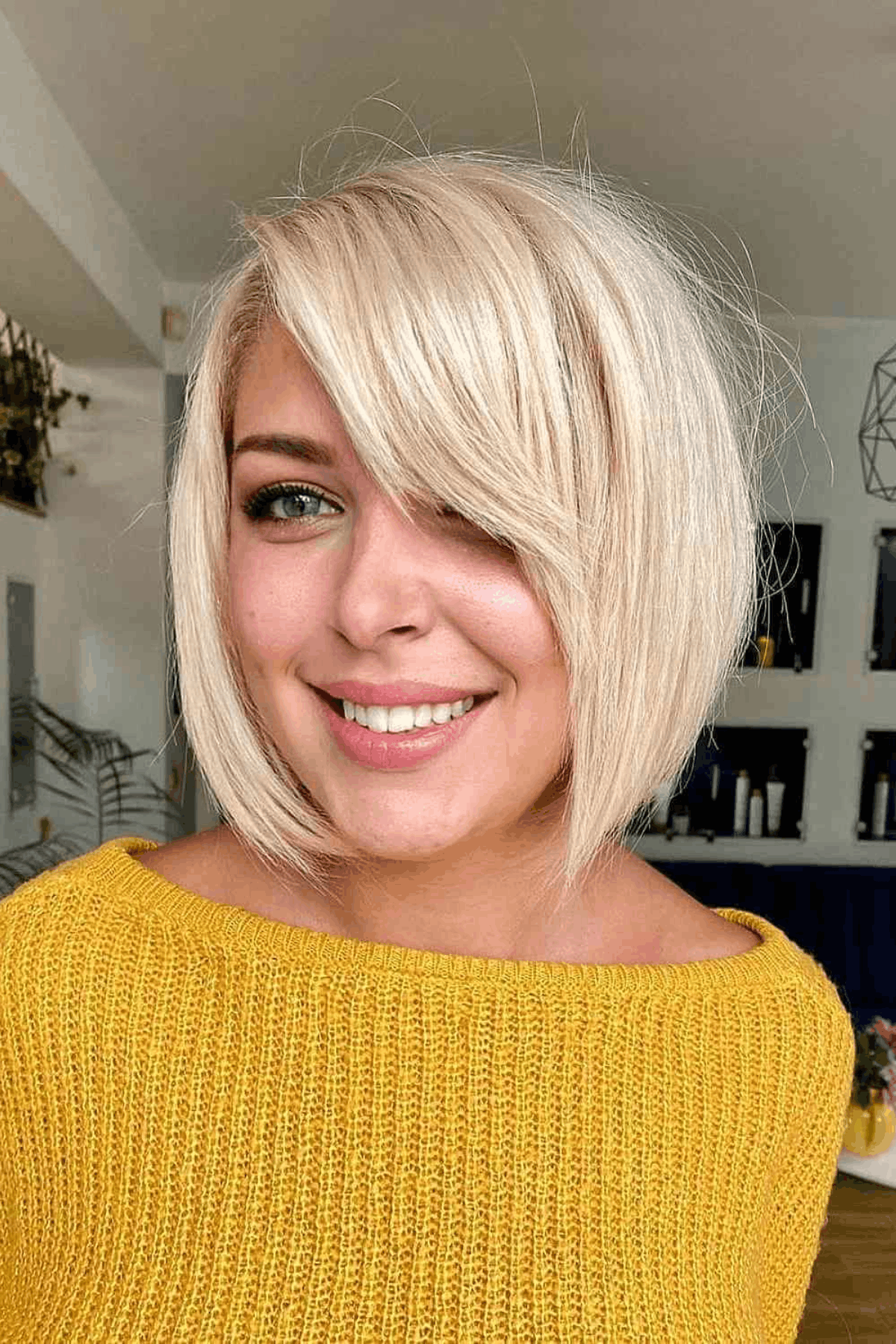 Portrait of a woman with a blonde asymmetrical layered bob, styled longer on one side with sweeping side bangs.