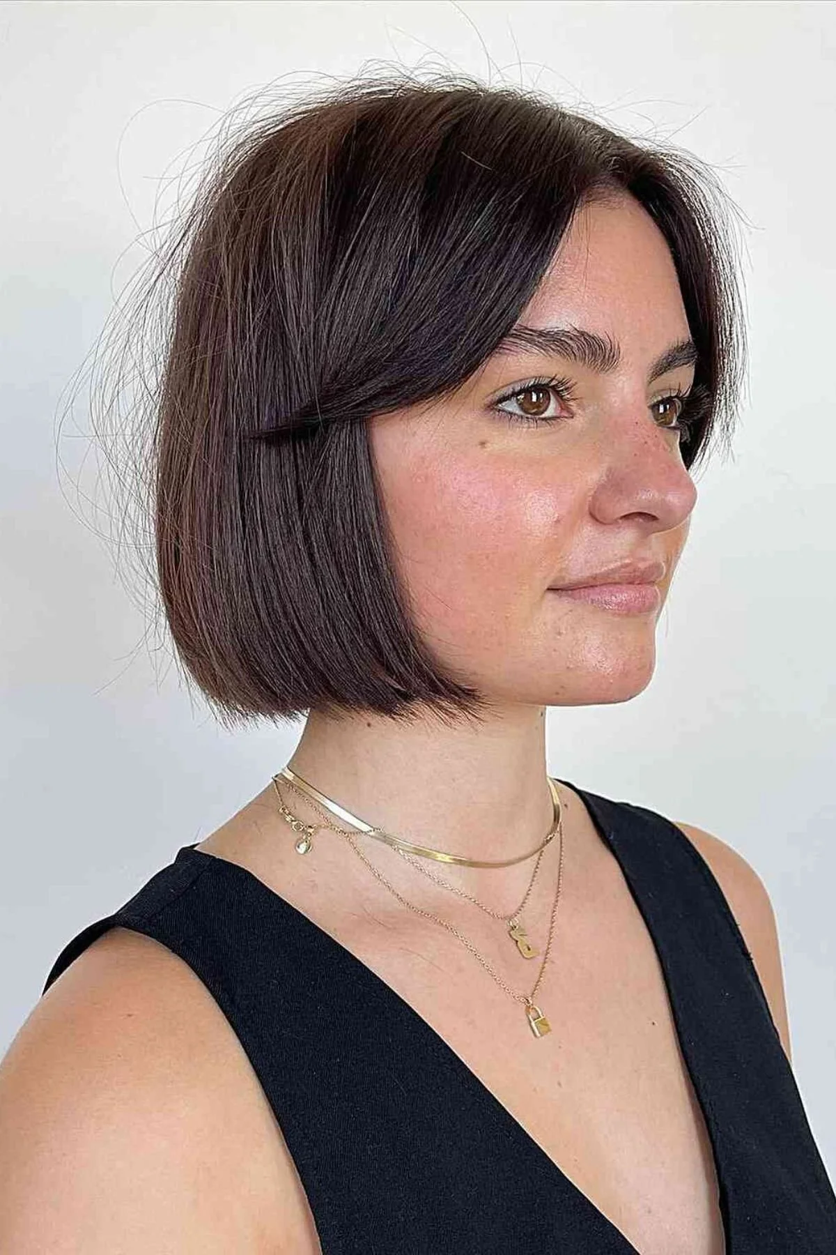 Girl wearing a Chin-Length Blunt Bob with Sleek Finish, featuring razor-sharp ends, smooth straight strands, and a glossy polished look.