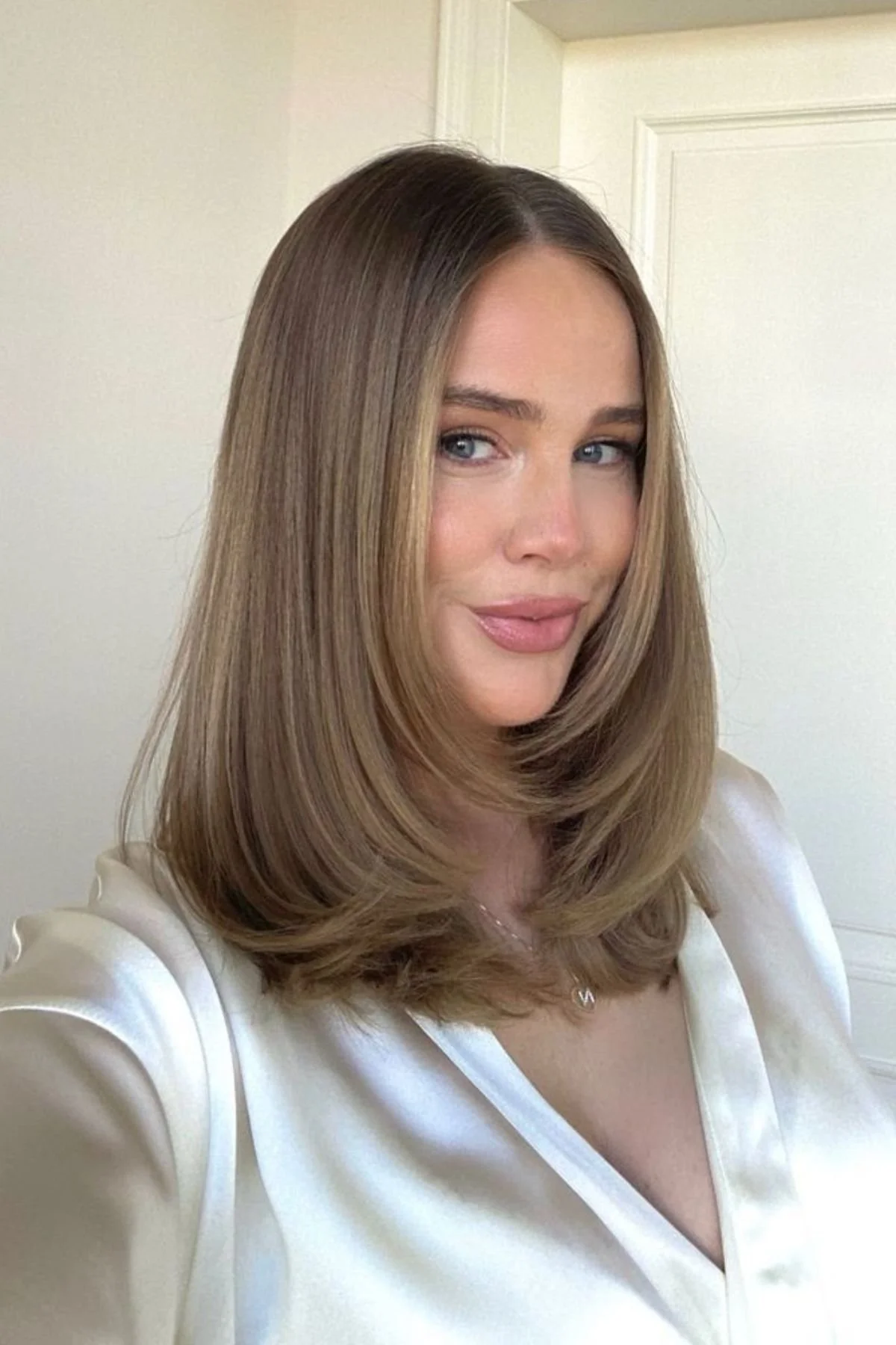 Girl styled in a Feathered Mid-Length Cut haircut with airy feathered layers that add bounce and softness.