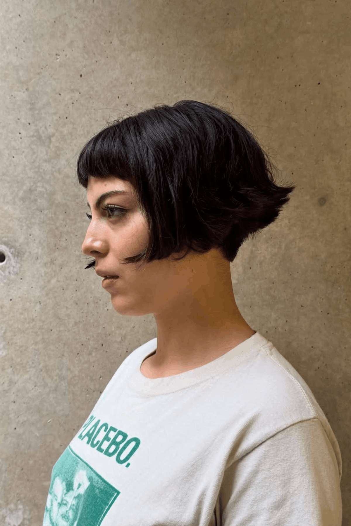 Side-profile image of a person wearing The Cropped Cut with Side Fringe, showing a short, cropped haircut with a soft side fringe, compact shape, and subtle layering around the ears and neckline.