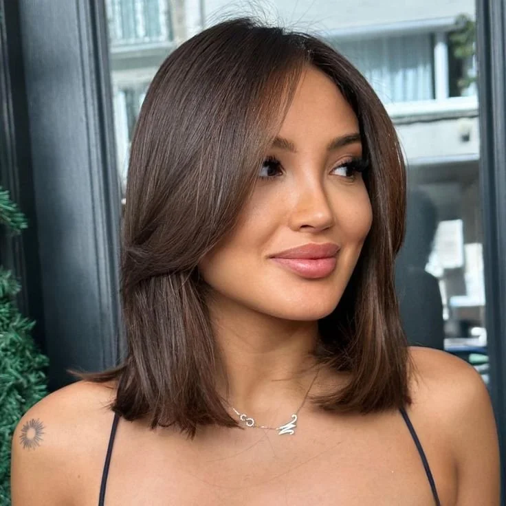 woman with a bob haircut styled with long curtain bangs, offering a chic and modern twist to a timeless short hairstyle.