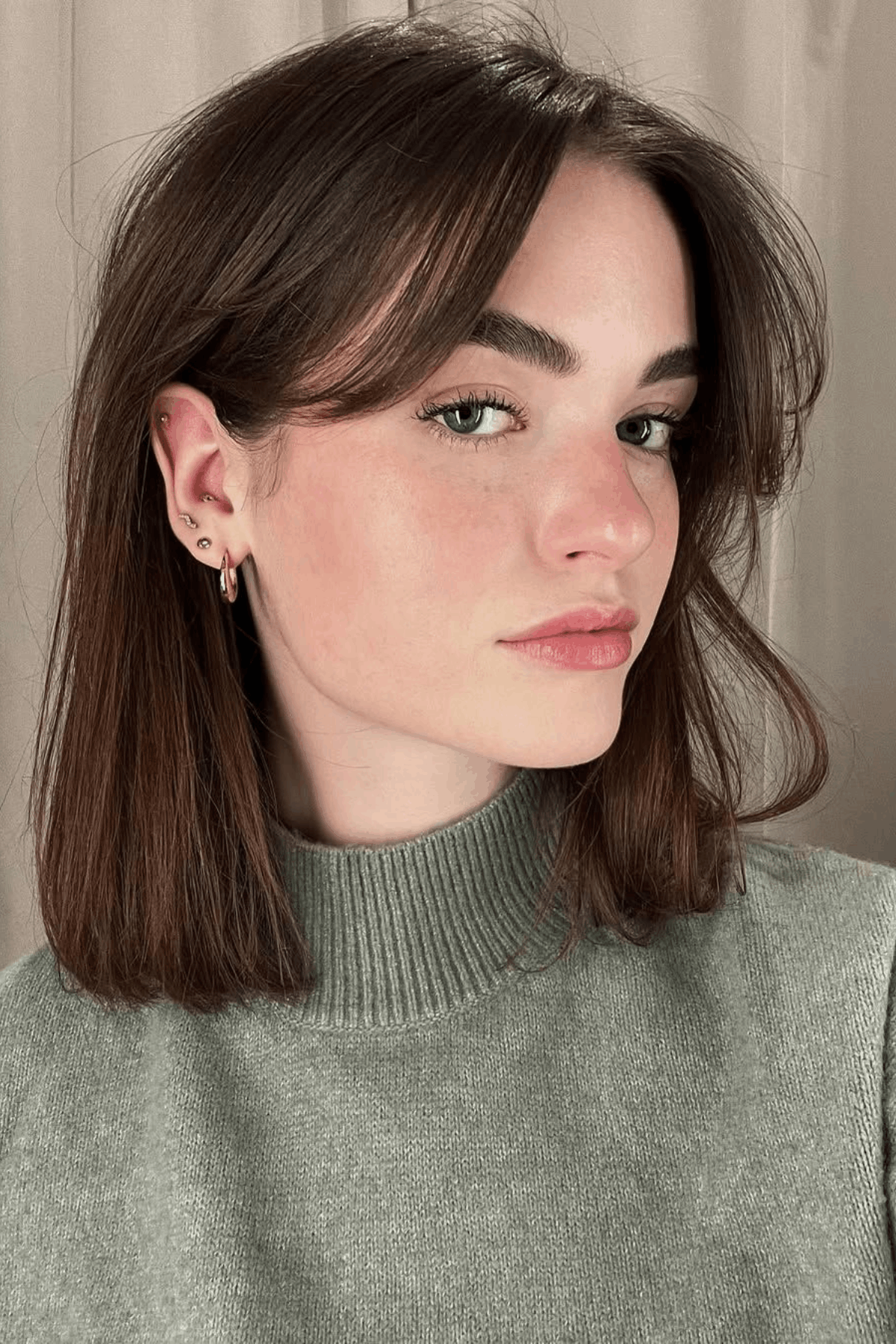 Woman with a short butterfly haircut for straight hair, featuring smooth, layered sections that frame the face with minimal texture and controlled volume.