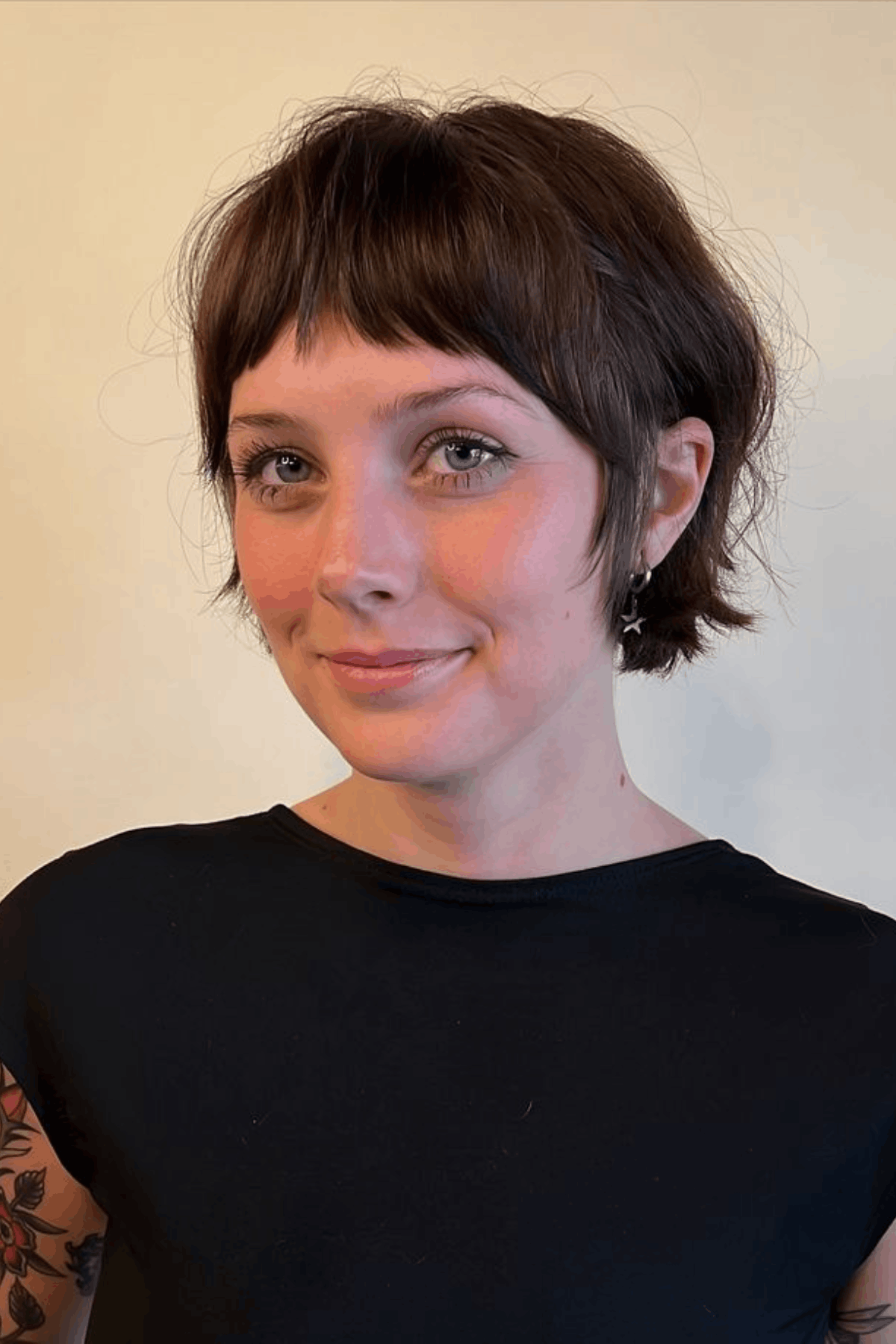 Front-facing image of a person wearing Fringed French Pixie with Airy Texture, defined by a short, softly cropped shape with a delicate fringe and light, airy texture throughout.