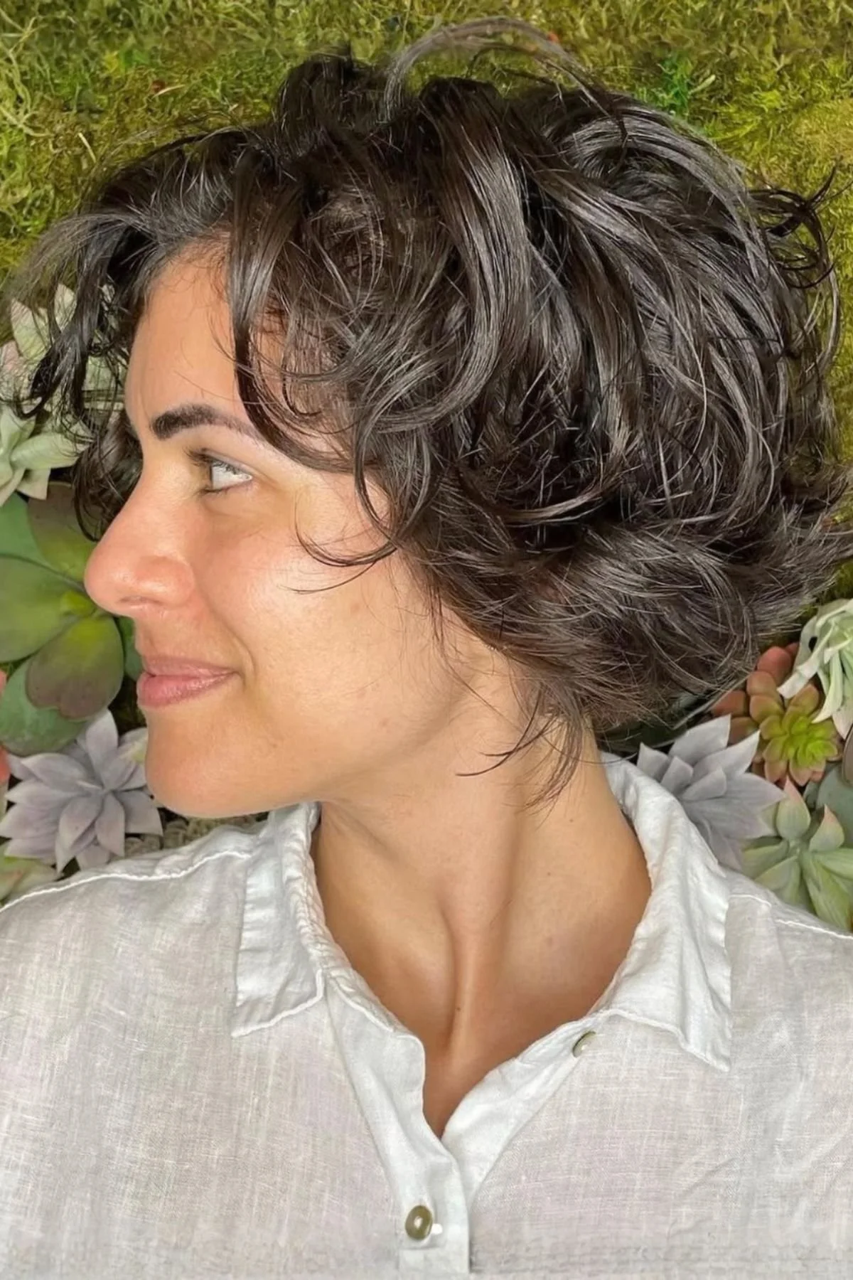Woman with a Wavy Bixie Haircut, styled with natural waves that enhance the layered pixie-bob hybrid shape.