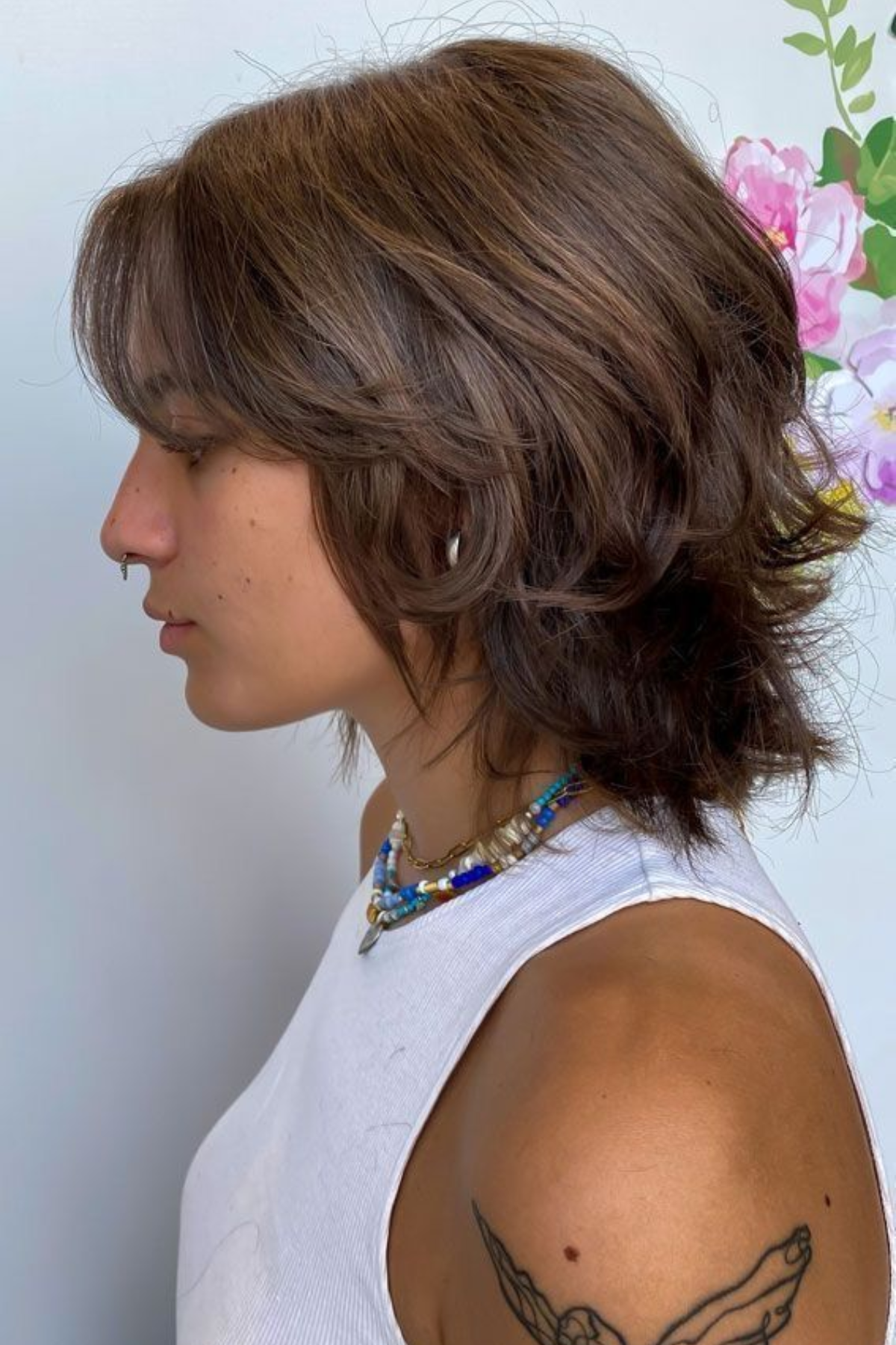 Woman styled in a Shaggy Wolf Cut haircut featuring layered volume at the crown and wispy ends for a bold textured look.