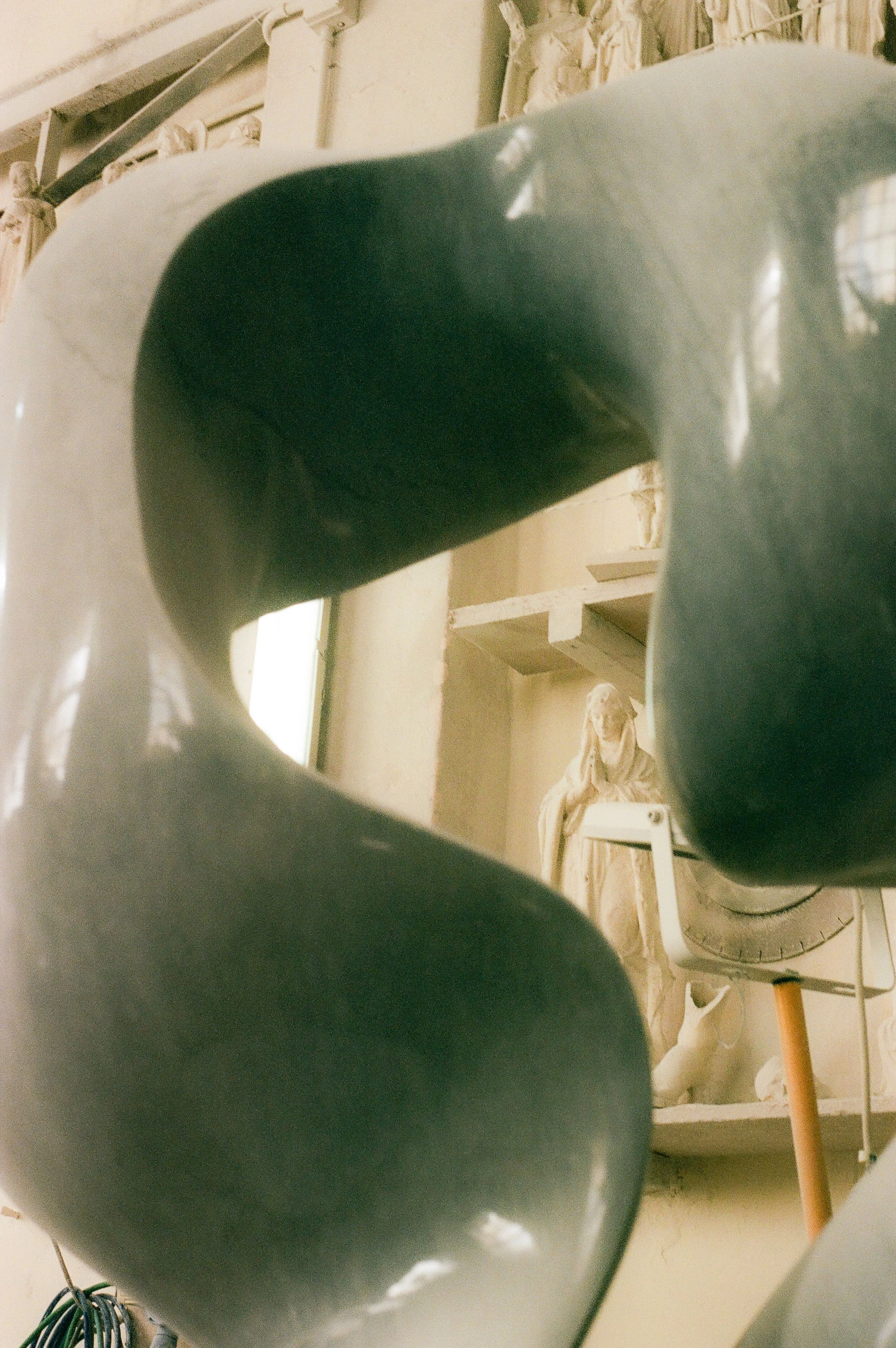 A reflection of a person taking a photo, seen through a round mirror, with a collection of sculptures and art pieces in the background.