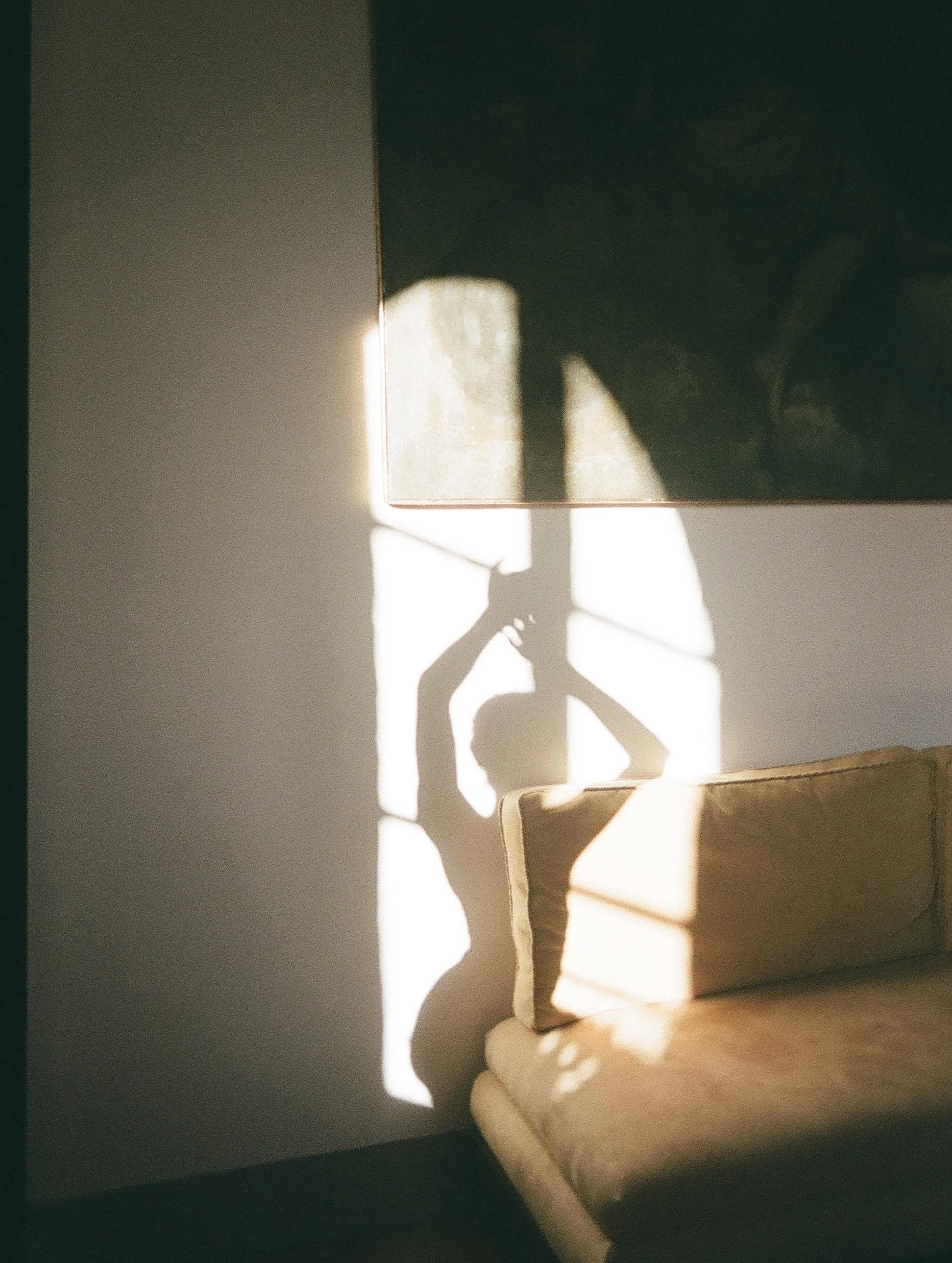 Sunlight creates shadow shapes on a wall, including a chair's shadow and a rectangular light pattern.