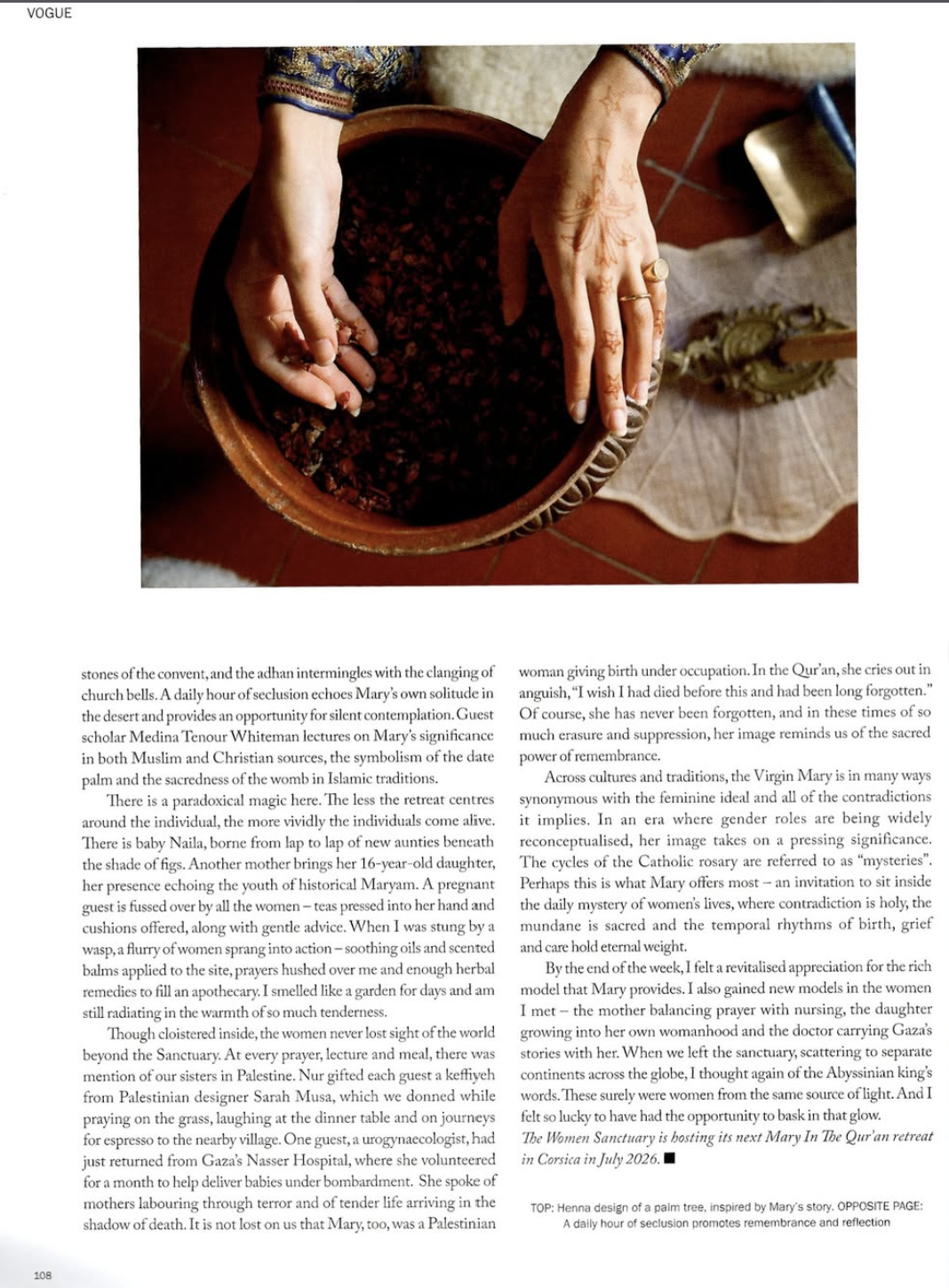 Hands with henna designs holding a bowl of dried red herbs or berries, seen from above, with a decorative tile floor and a beige cloth in the background.