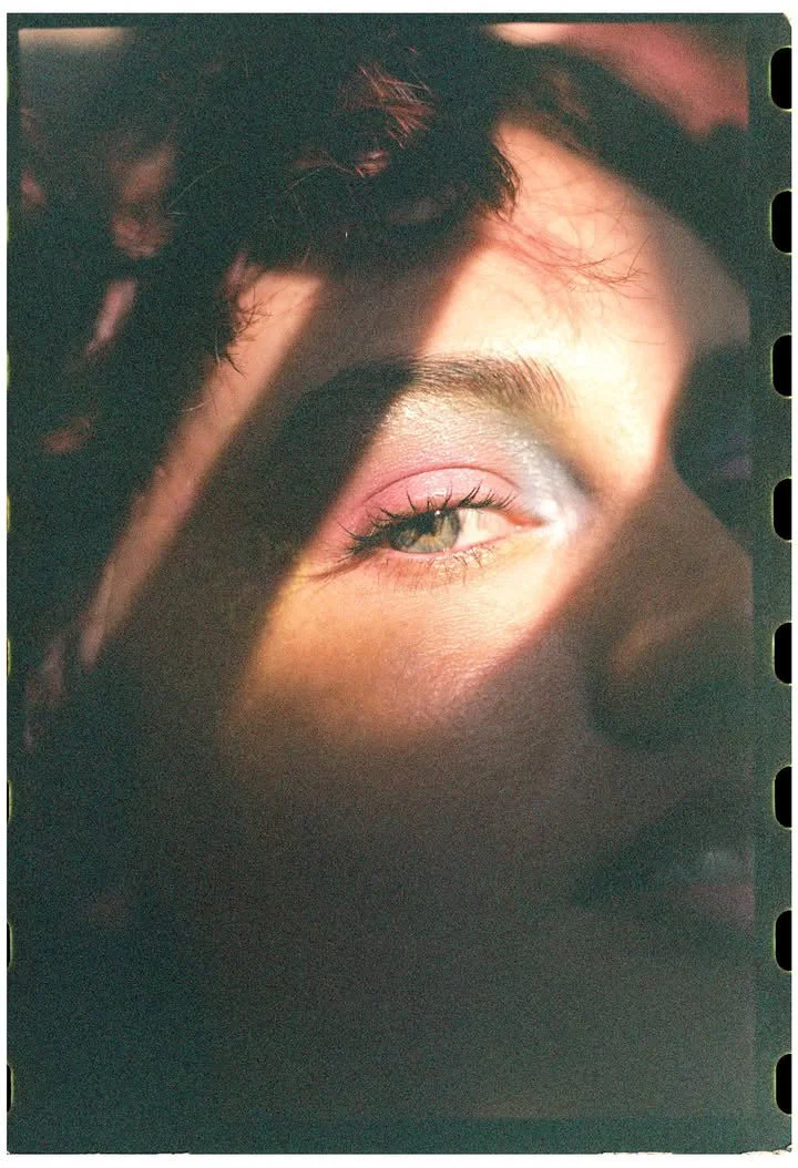 Close-up of a person's eye and brow illuminated by sunlight, with part of their face in shadow.