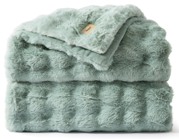 A stack of three folded plush, mint green blankets or throws, with the top one showing a beige tag.