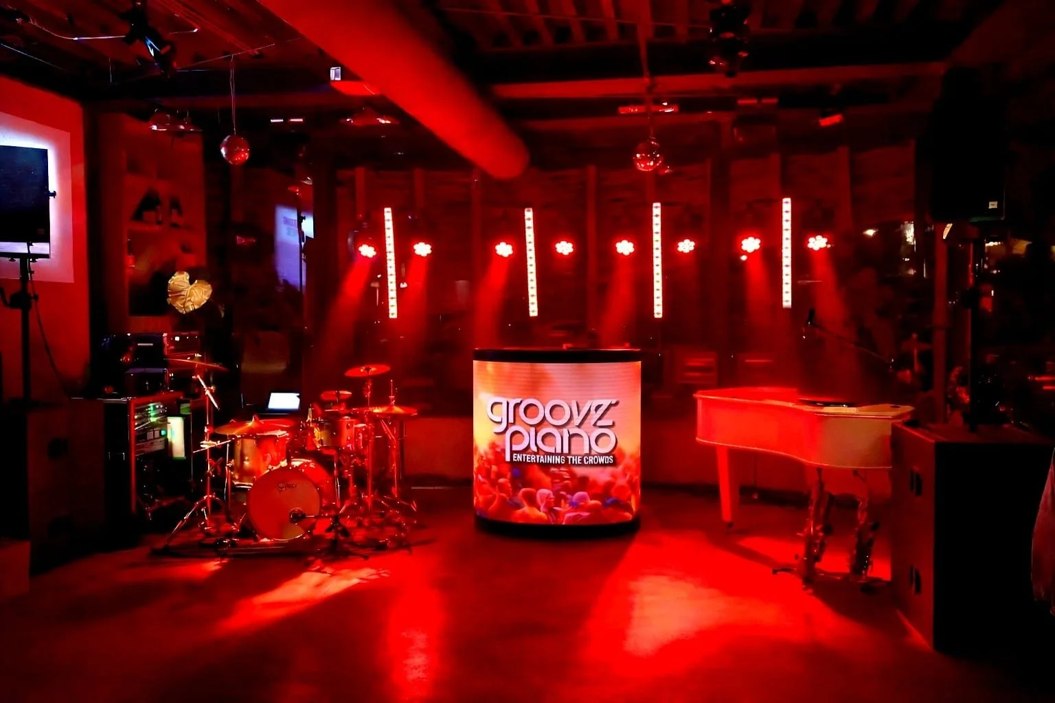 Vooraanzicht van de XL-bandopstelling. 3-mans formatie met interactieve DJ-tafel, drumstel en piano.