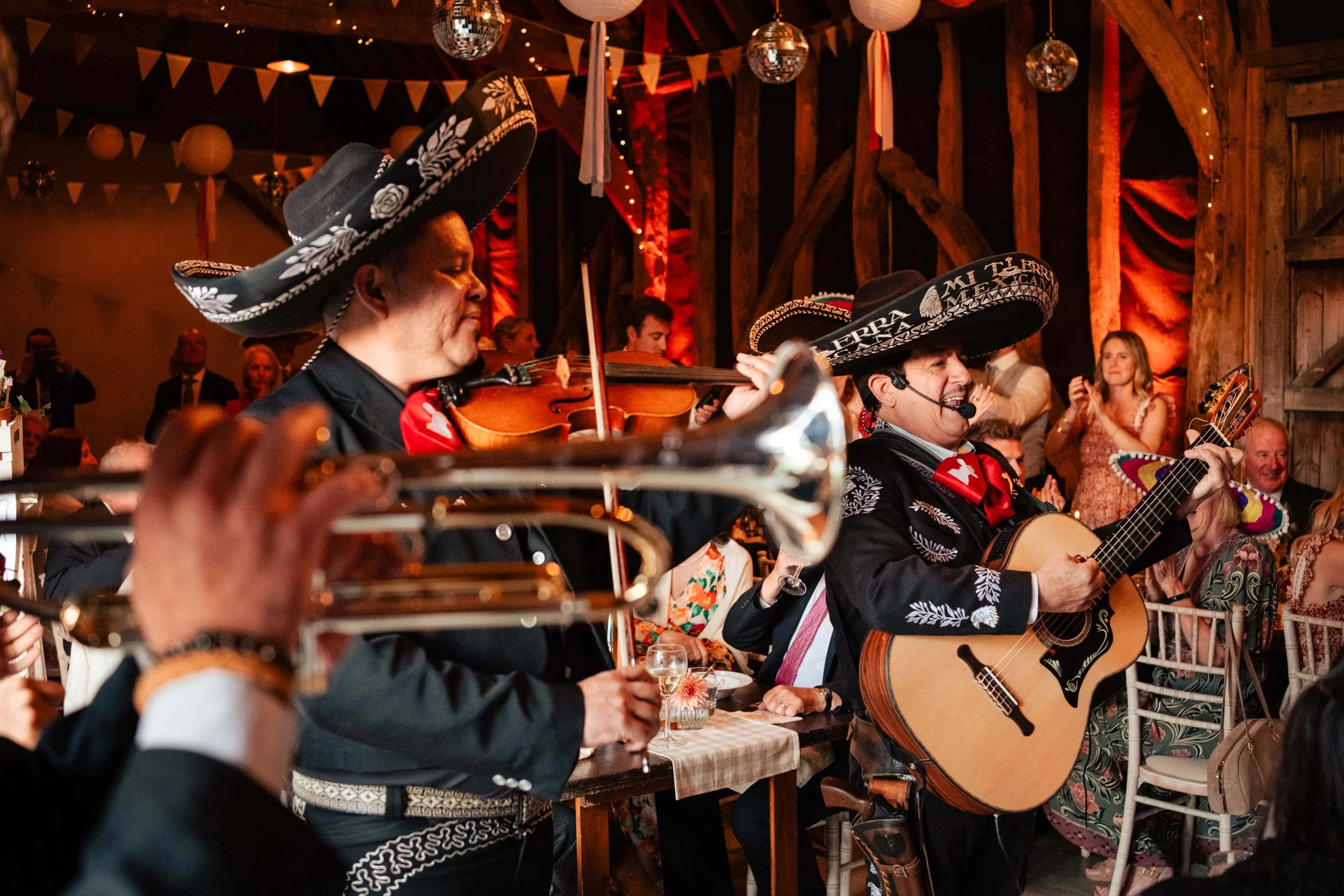 Mexican musicians wearing traditional sombreros playing instruments at a festive event.