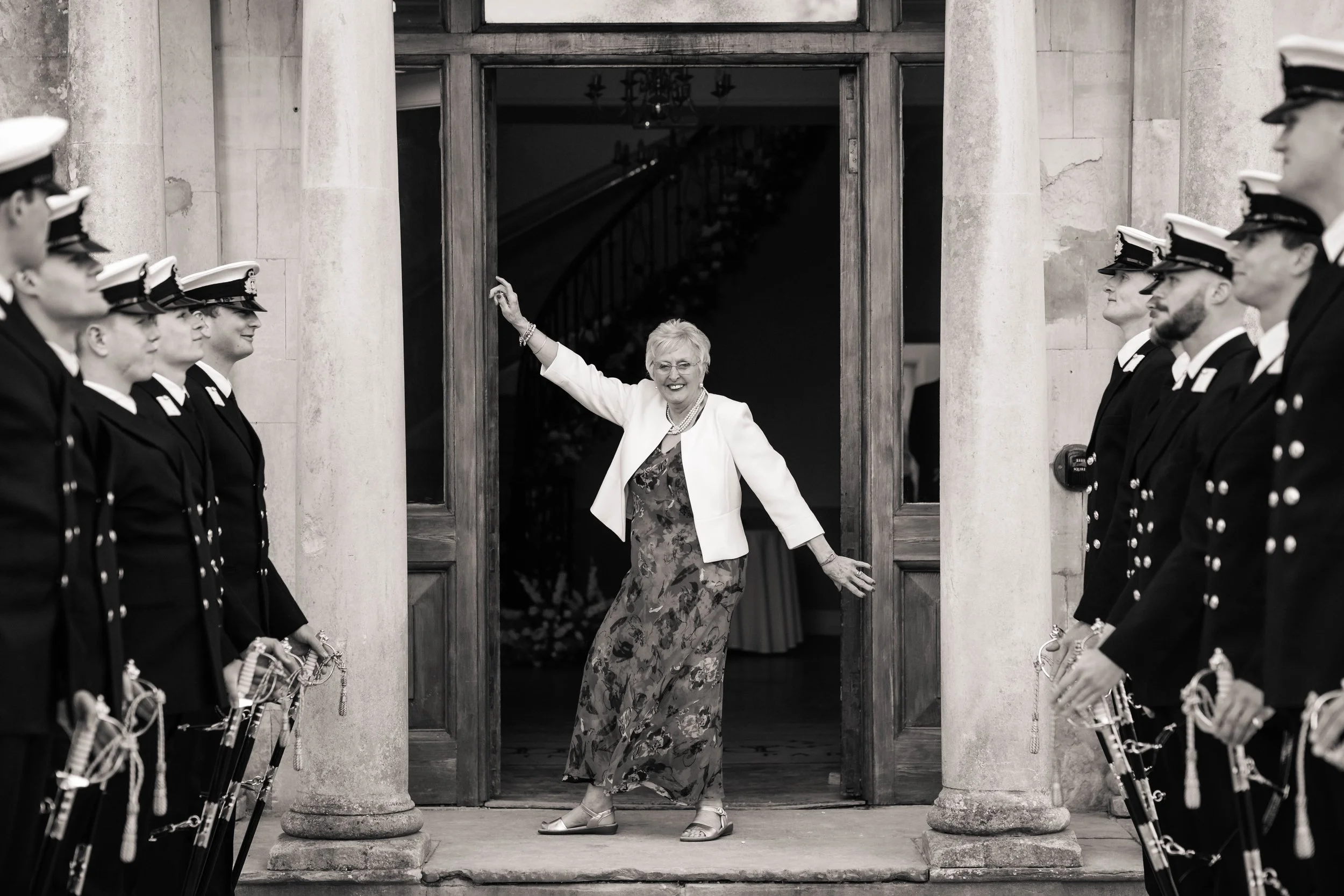 Grandmother striking a pose as she walks through a guard of honour at a wedding ceremony.