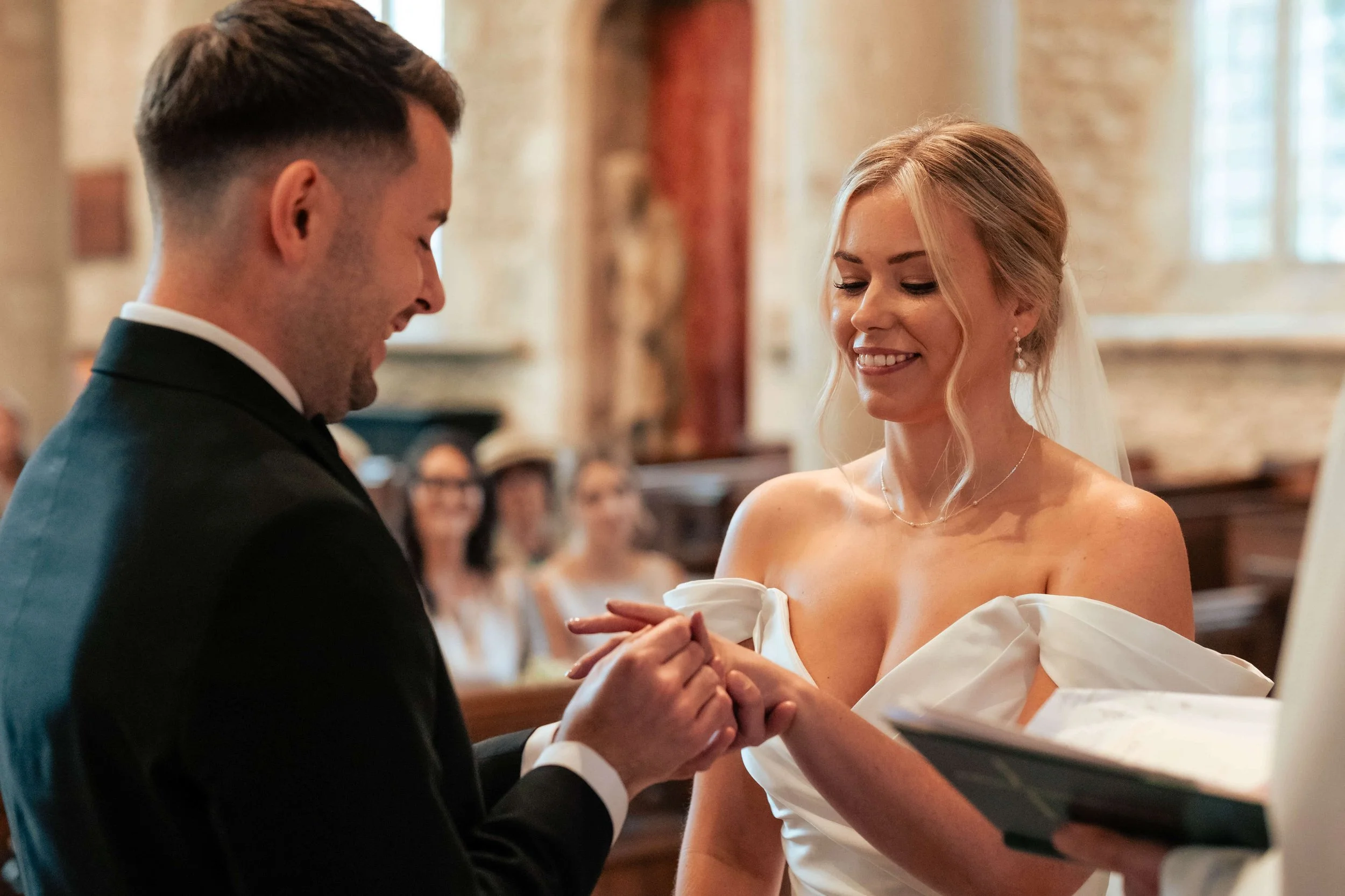 A bride and groom exchanging rings at their wedding ceremony inside a church.