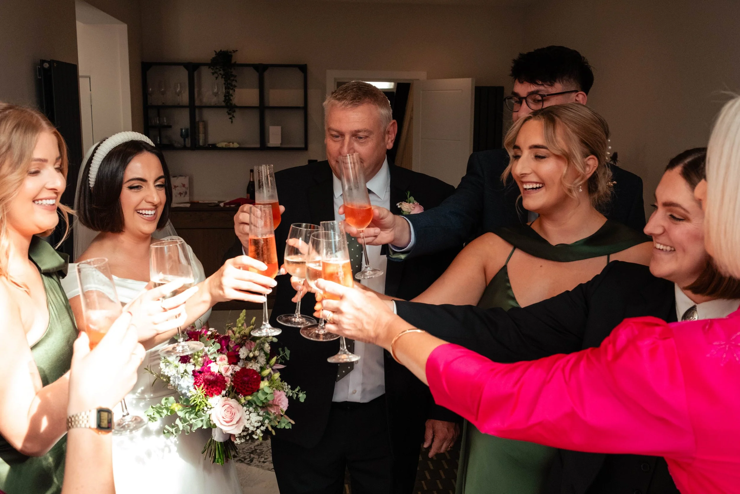 Group of friends celebrating with champagne toast at a wedding reception.