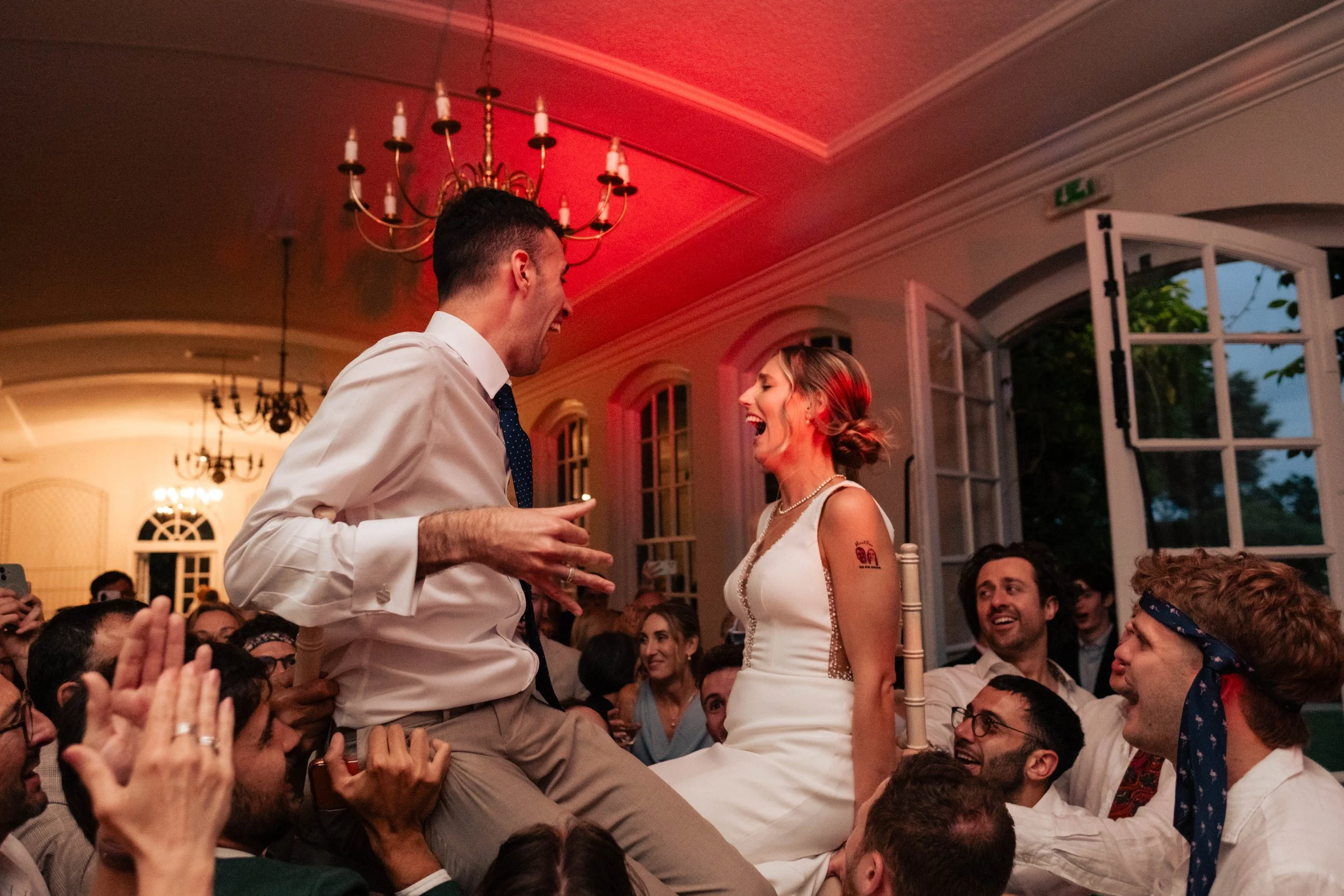 Bride and groom lifted on chairs during traditional Israeli dancing at their wedding reception.