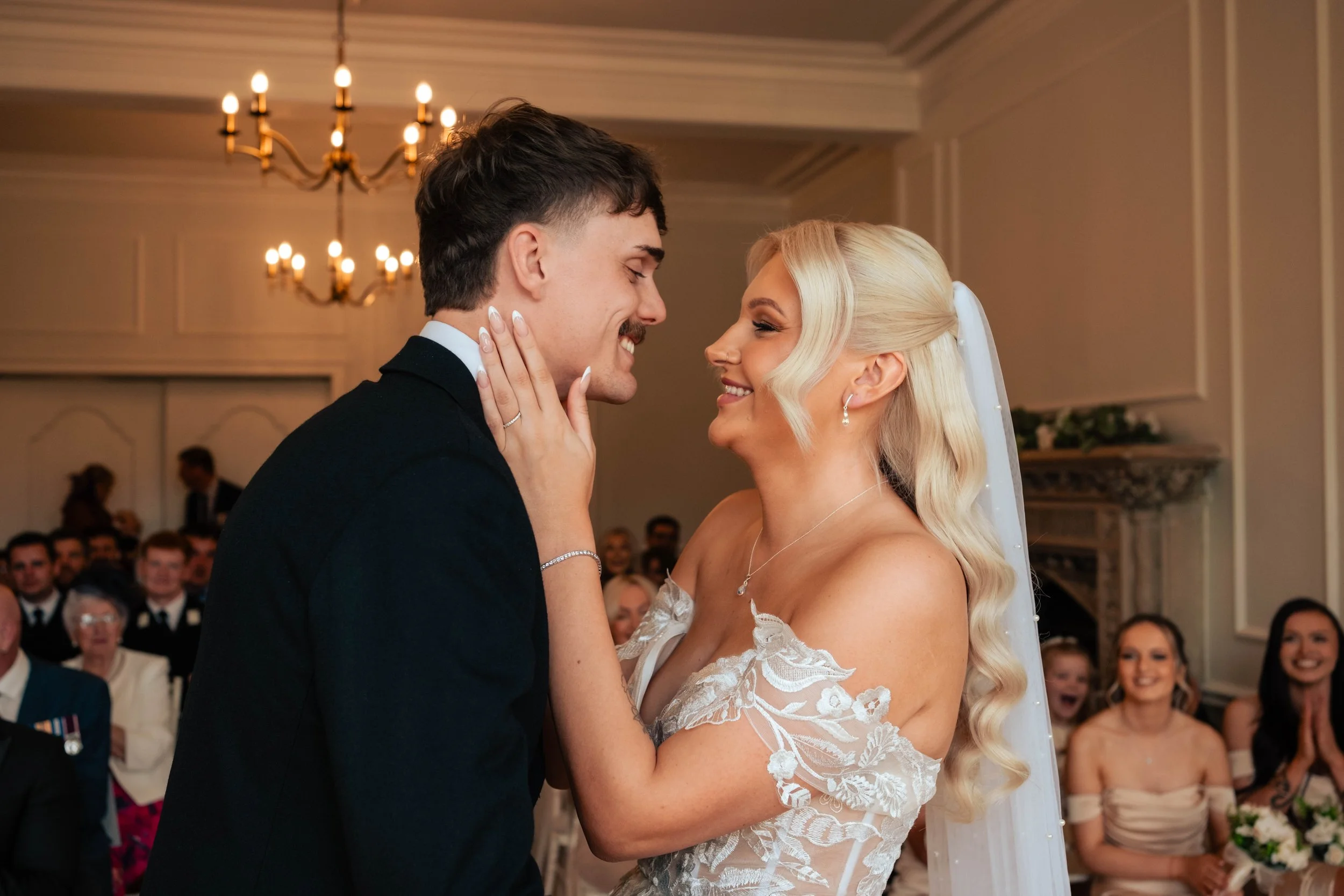 Bride and groom smiling at each other just before kissing during their wedding ceremony at Eastington Park.