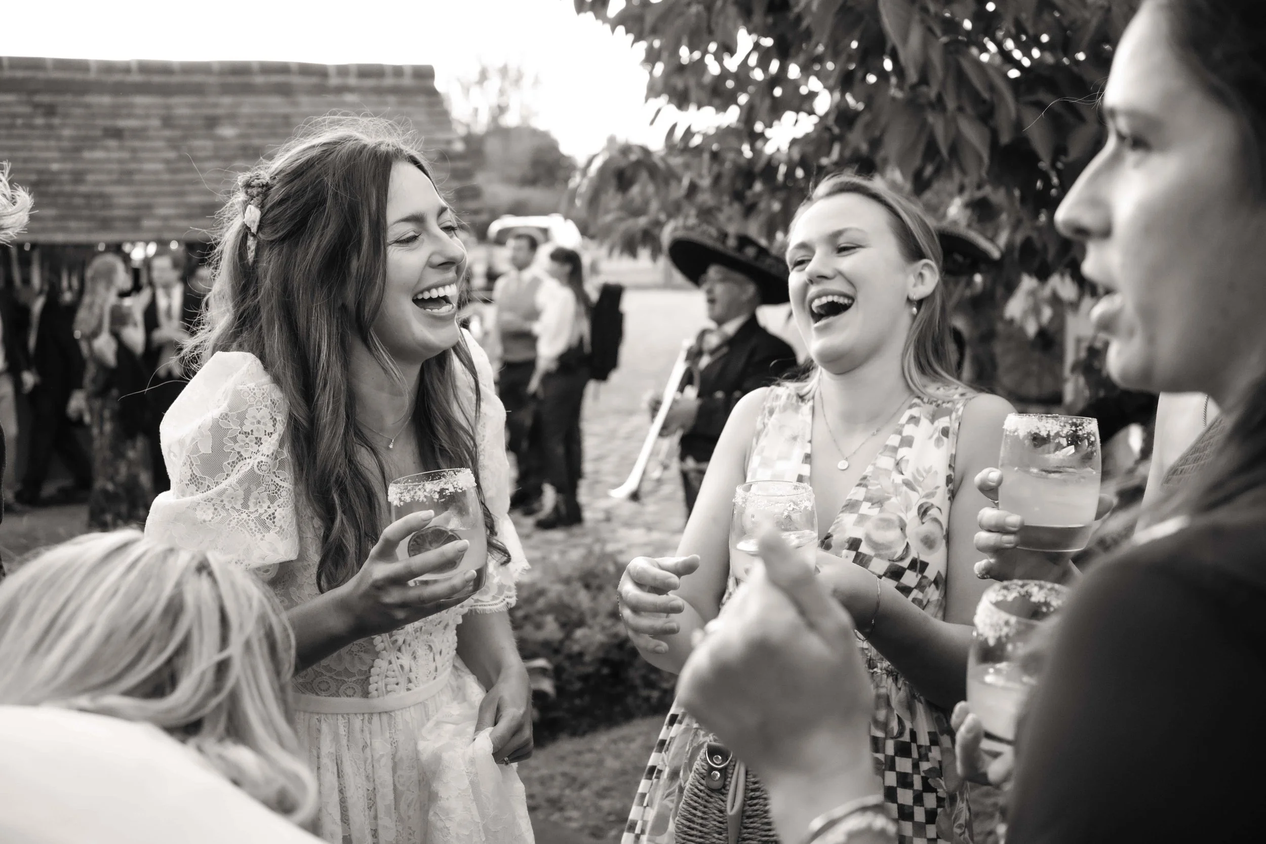 People at a celebration outdoors, laughing and holding drinks with salt on the rims, in a lively social gathering.