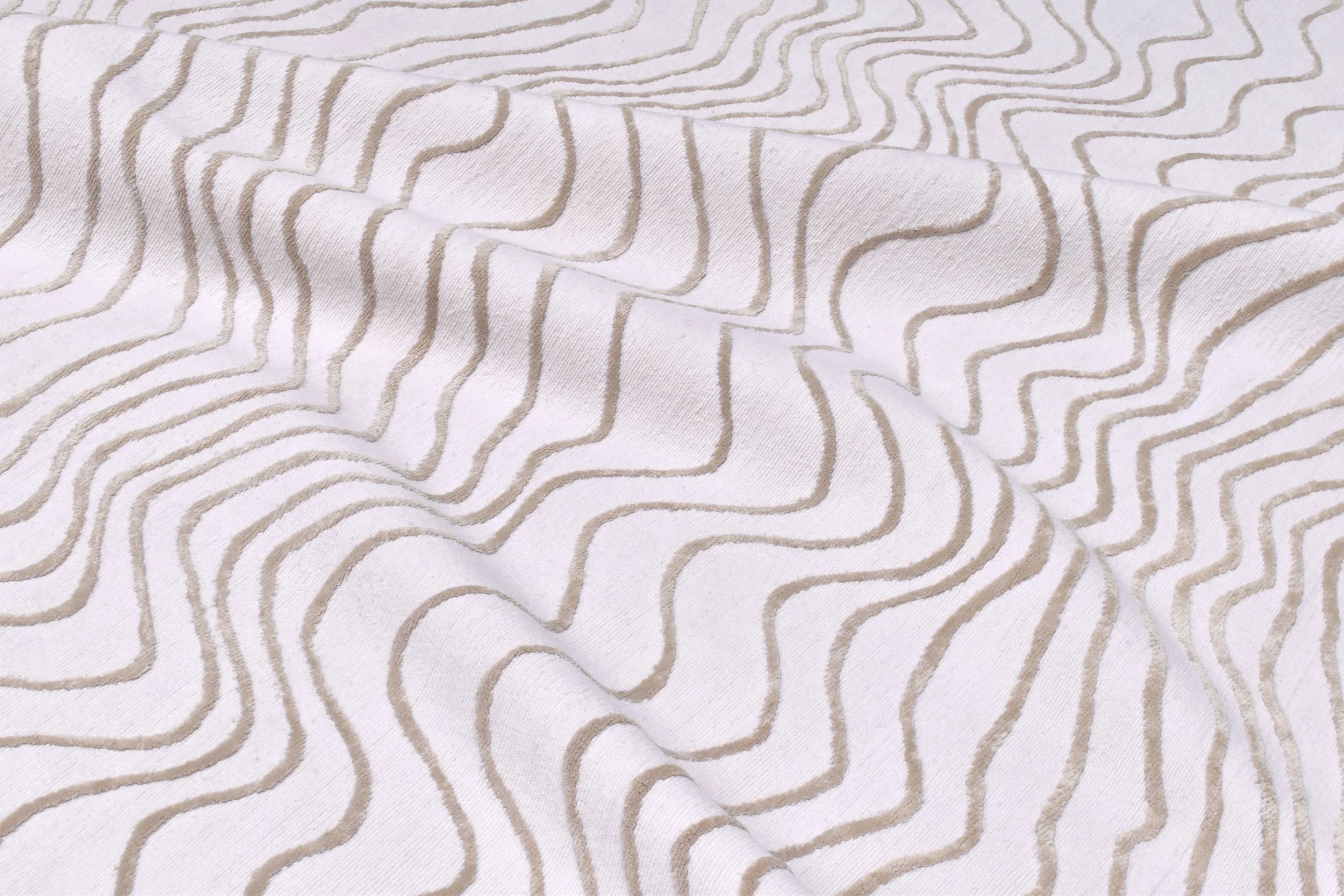 Close-up of white fabric with beige wavy lines forming a geometric pattern.