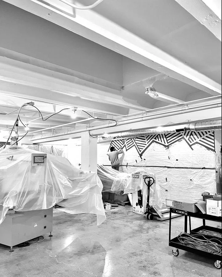 Ashley painting a pattern on the wall at the new print shop